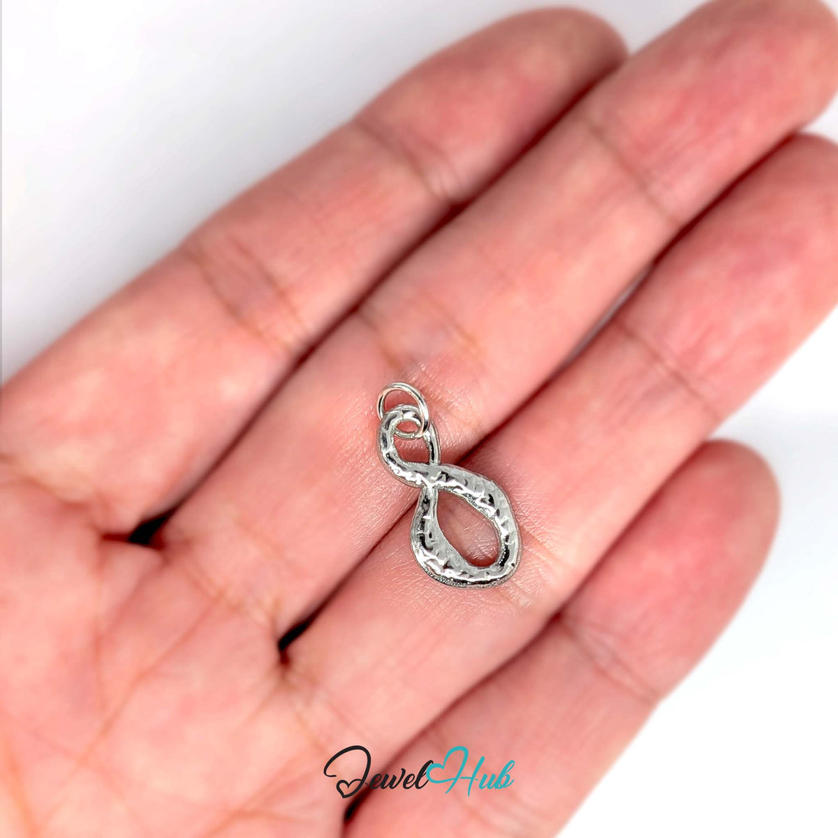 Textured infinity charm held in a hand to show its size - JewelHub