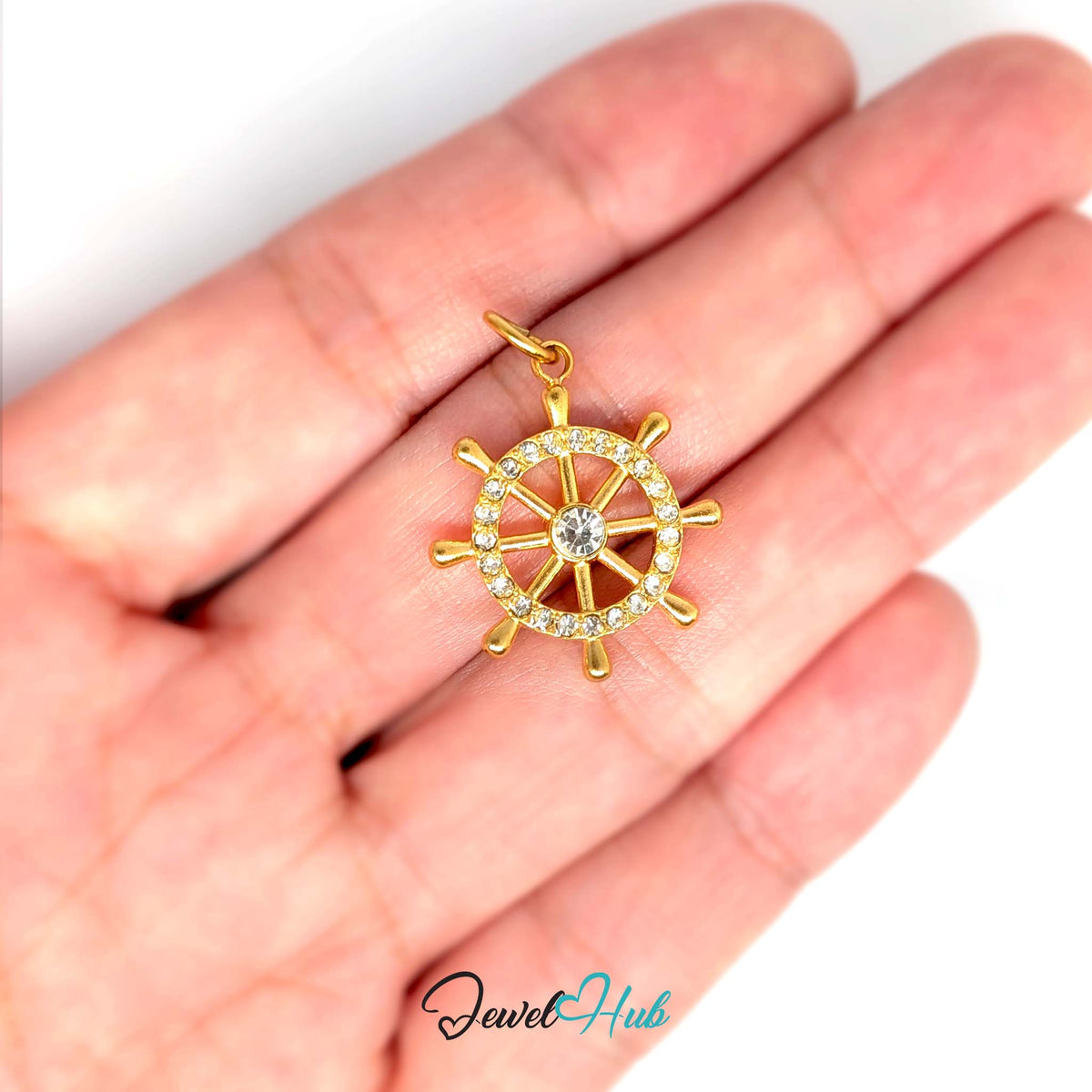 Ship wheel charm held in a hand to show its size - JewelHub
