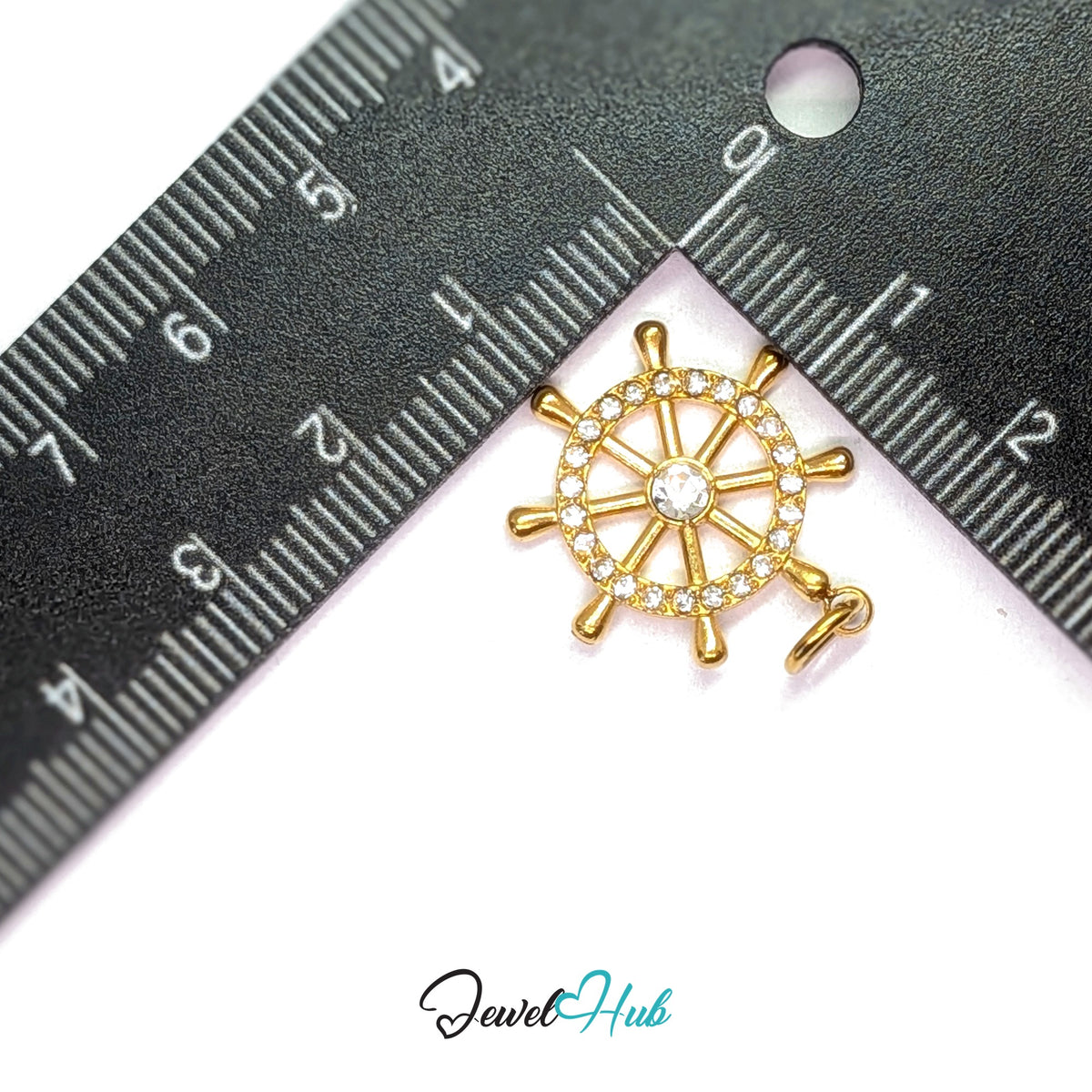 Ship wheel charm measured against a ruler at 19.8mm wide by 22.8mm tall - JewelHub