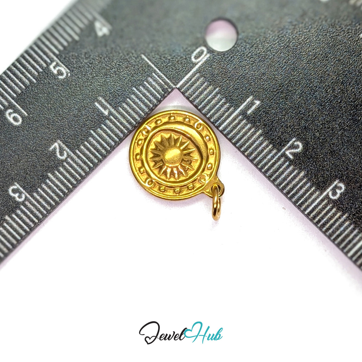 Sun medallion charm measured against a ruler at 15.3mm wide by 18.4mm tall - JewelHub