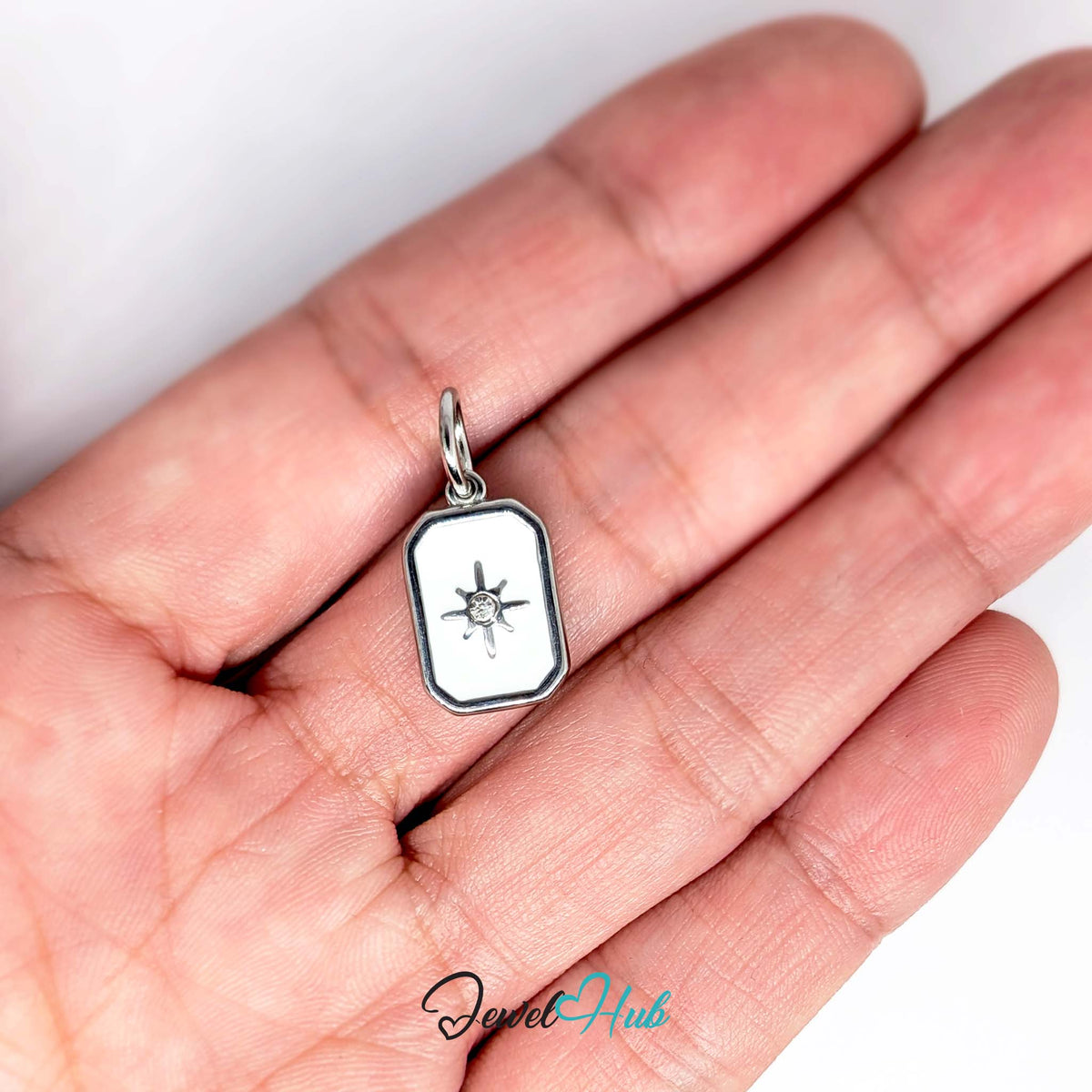 White star tag charm held in a hand to show its size - JewelHub