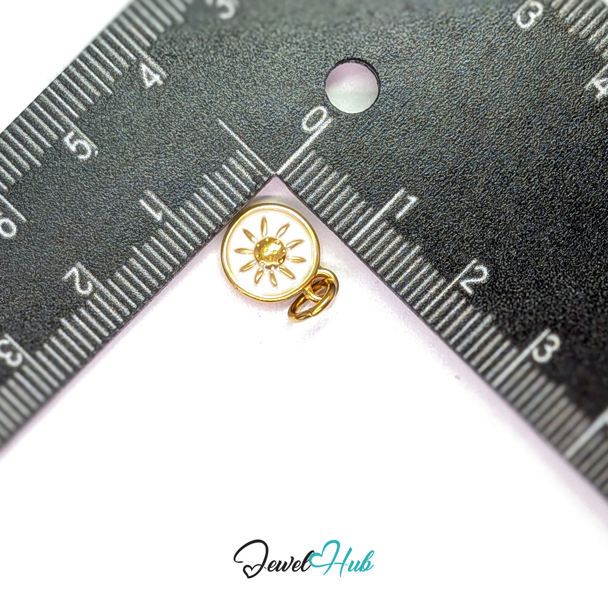 White sun charm measured against a ruler at 10mm wide by 12.8mm tall - JewelHub