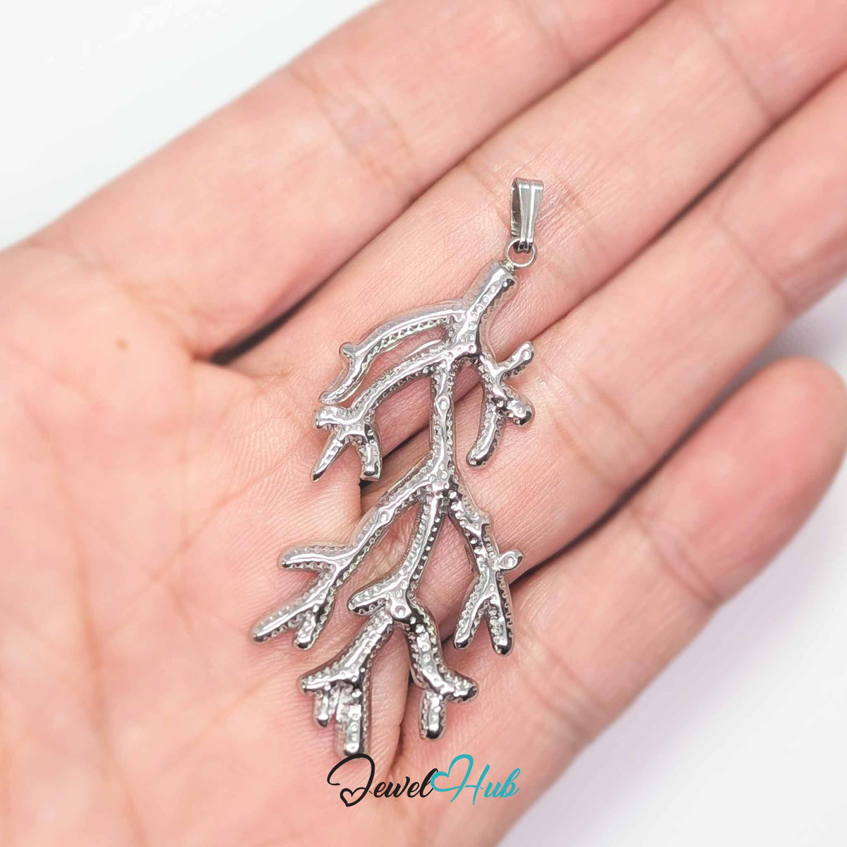 Silver Coral Seaweed pendant in silver-tone stainless steel - held in the hand to show size - JewelHub