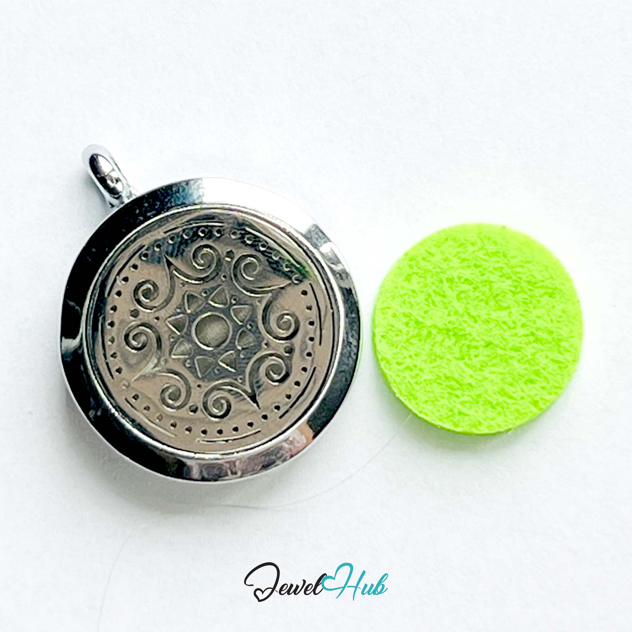 Silver pendant with intricate design next to a green cleaning sponge on a white background, branded 'Jewel Hub'.