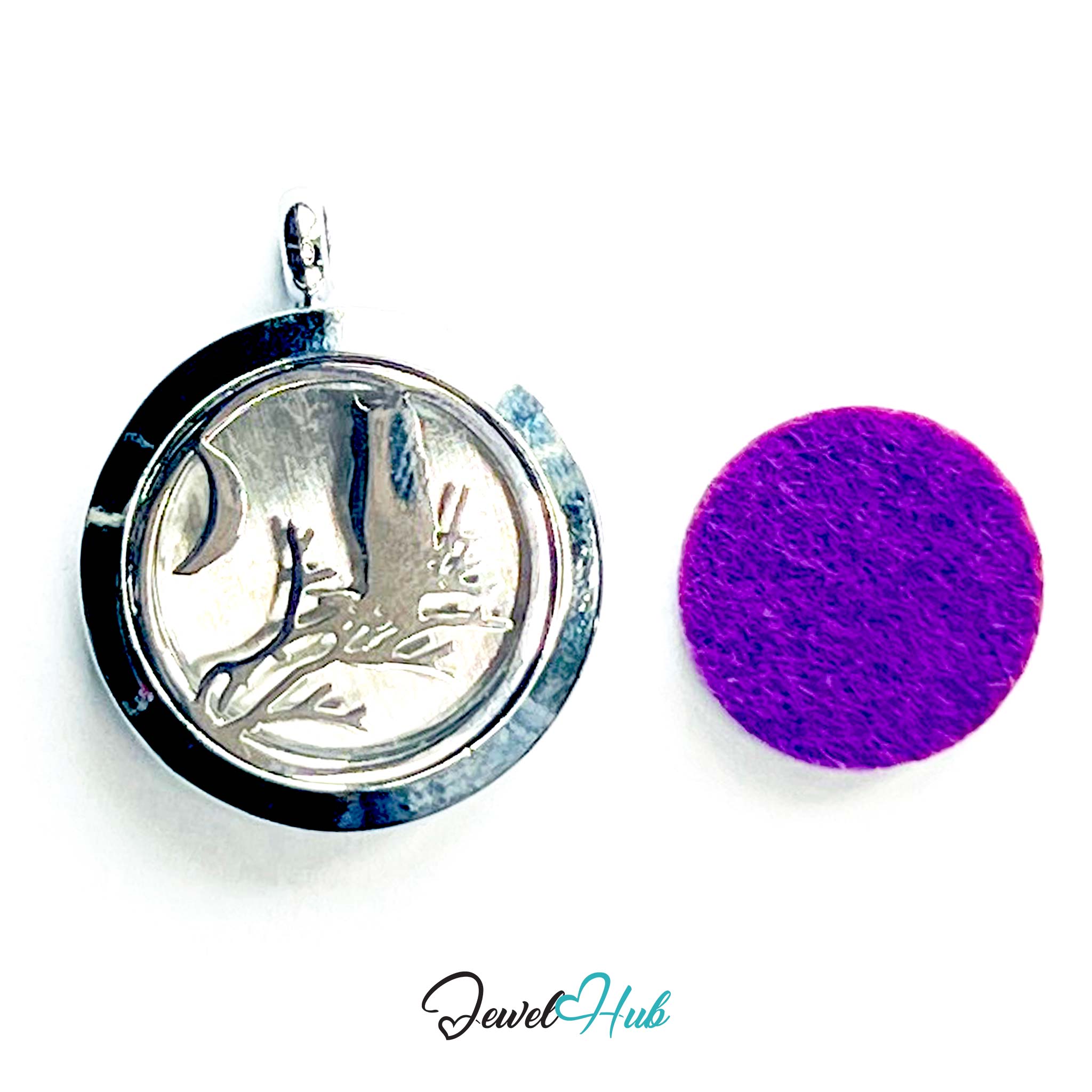 Silver pendant with engraved design on a white background, next to a purple round object.