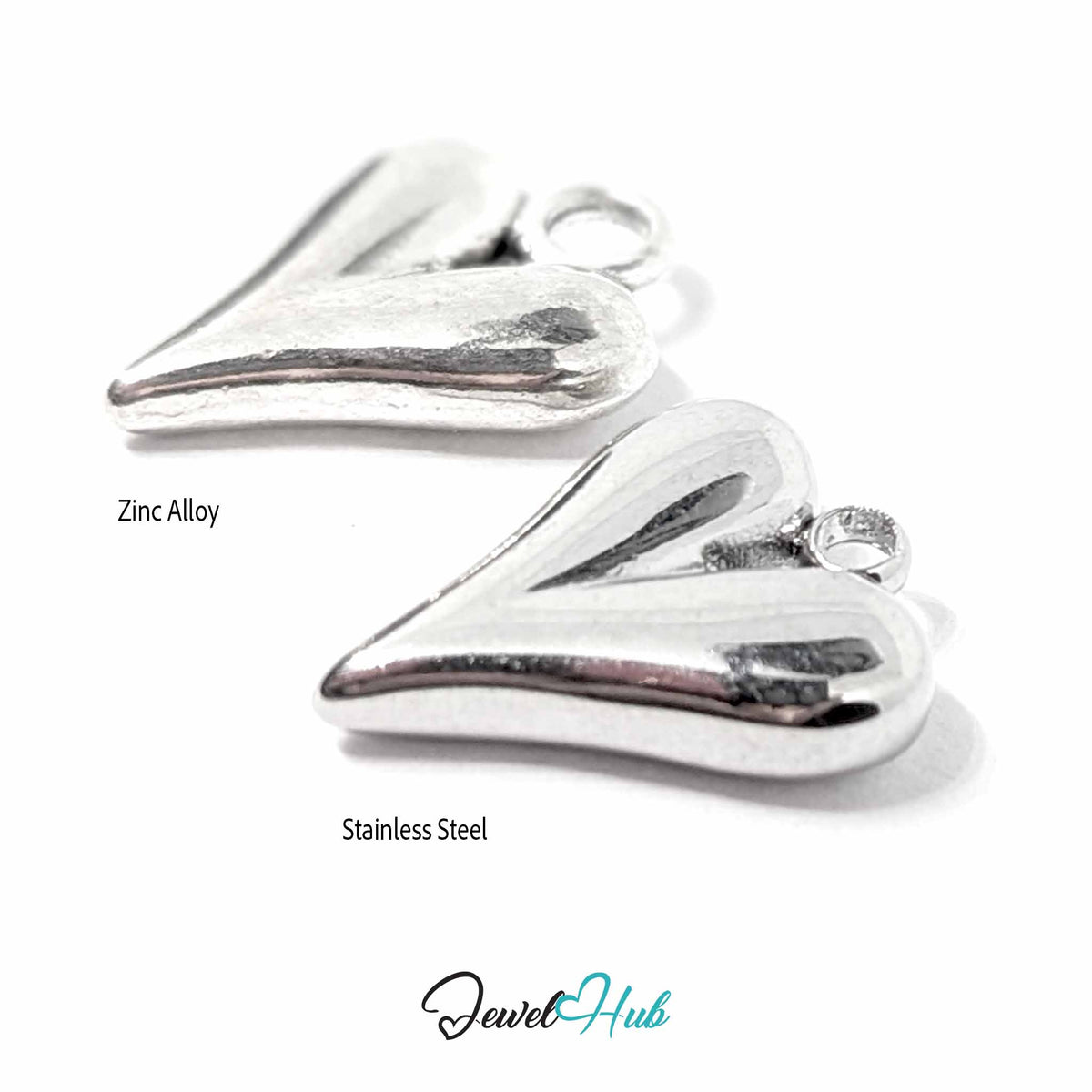 Zinc alloy and stainless steel heart pendants lying at an angle, showing thickness and polished finish - JewelHub