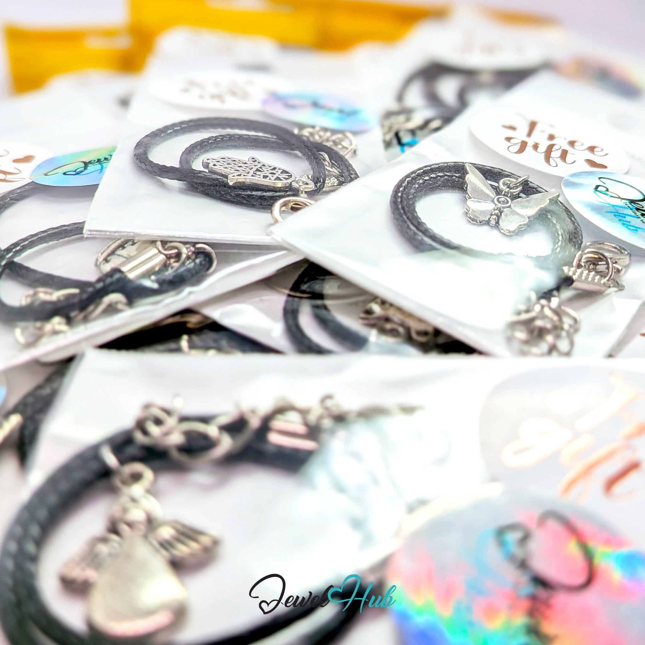 Sealed Free Gift bags, each holding a black faux leather cord bracelet with a silver tone charm attached