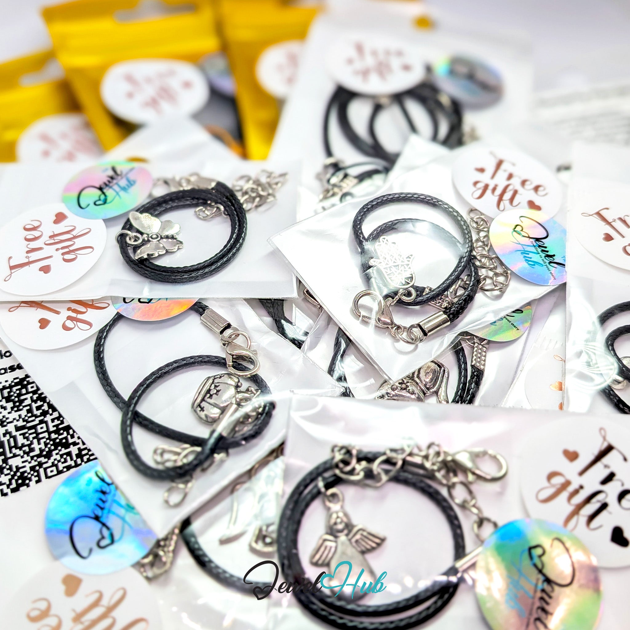 Free Gift bags spread out, each with a black cord bracelet and a single silver tone charm