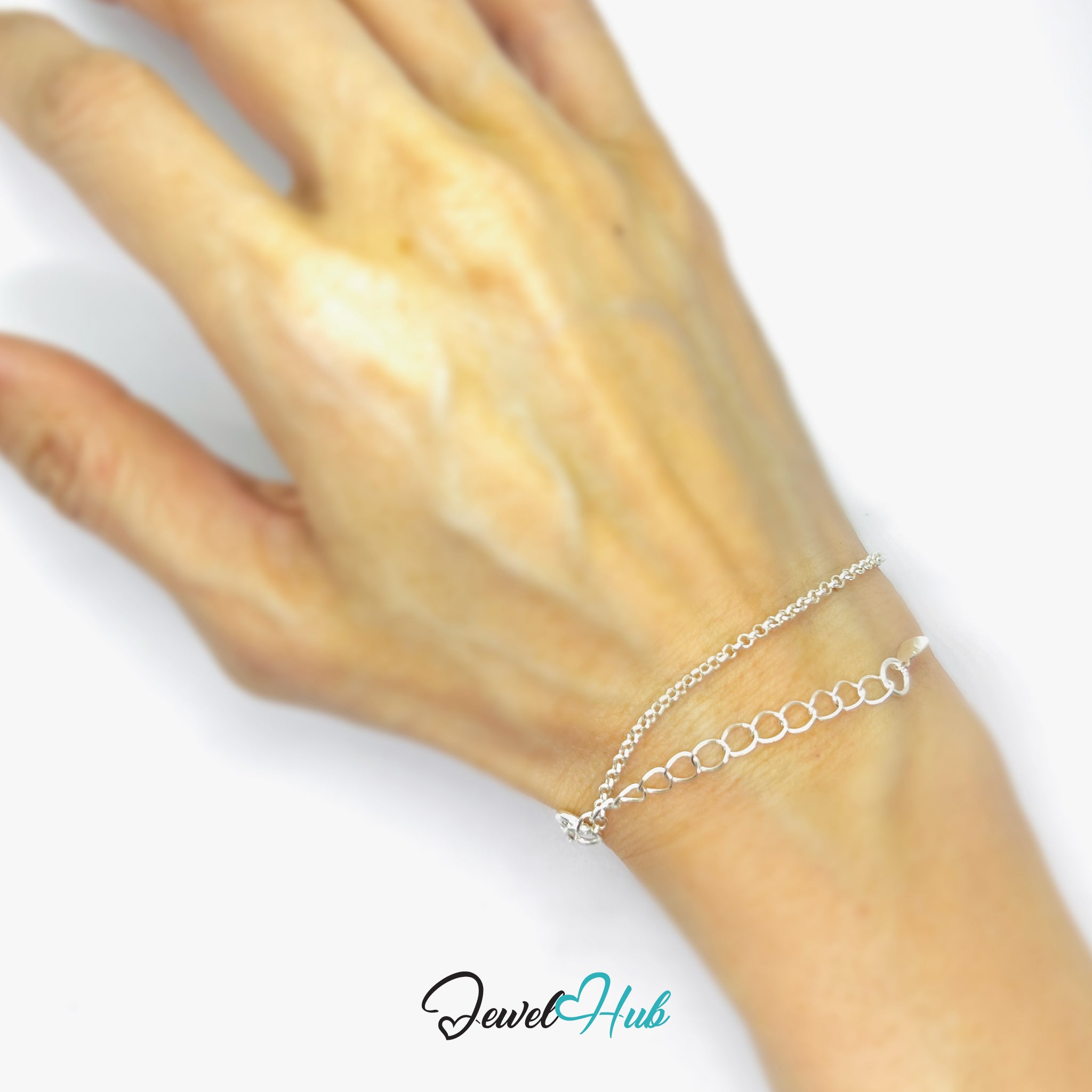 Silver bracelet on a wrist with a plain background, featuring the brand 'Jewel Hub'.