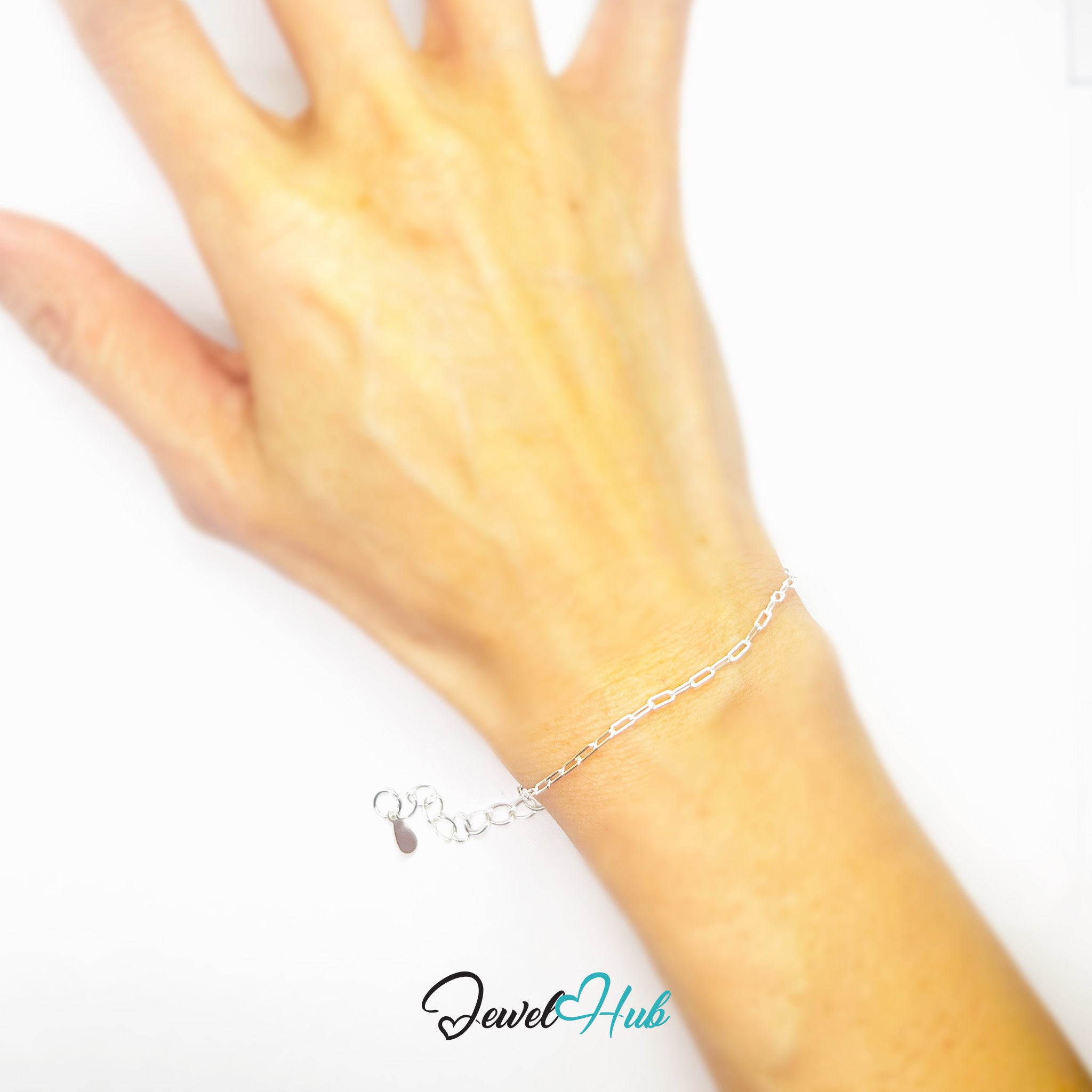 Silver bracelet on a wrist with a white background, featuring the brand 'Jewel Hub'.