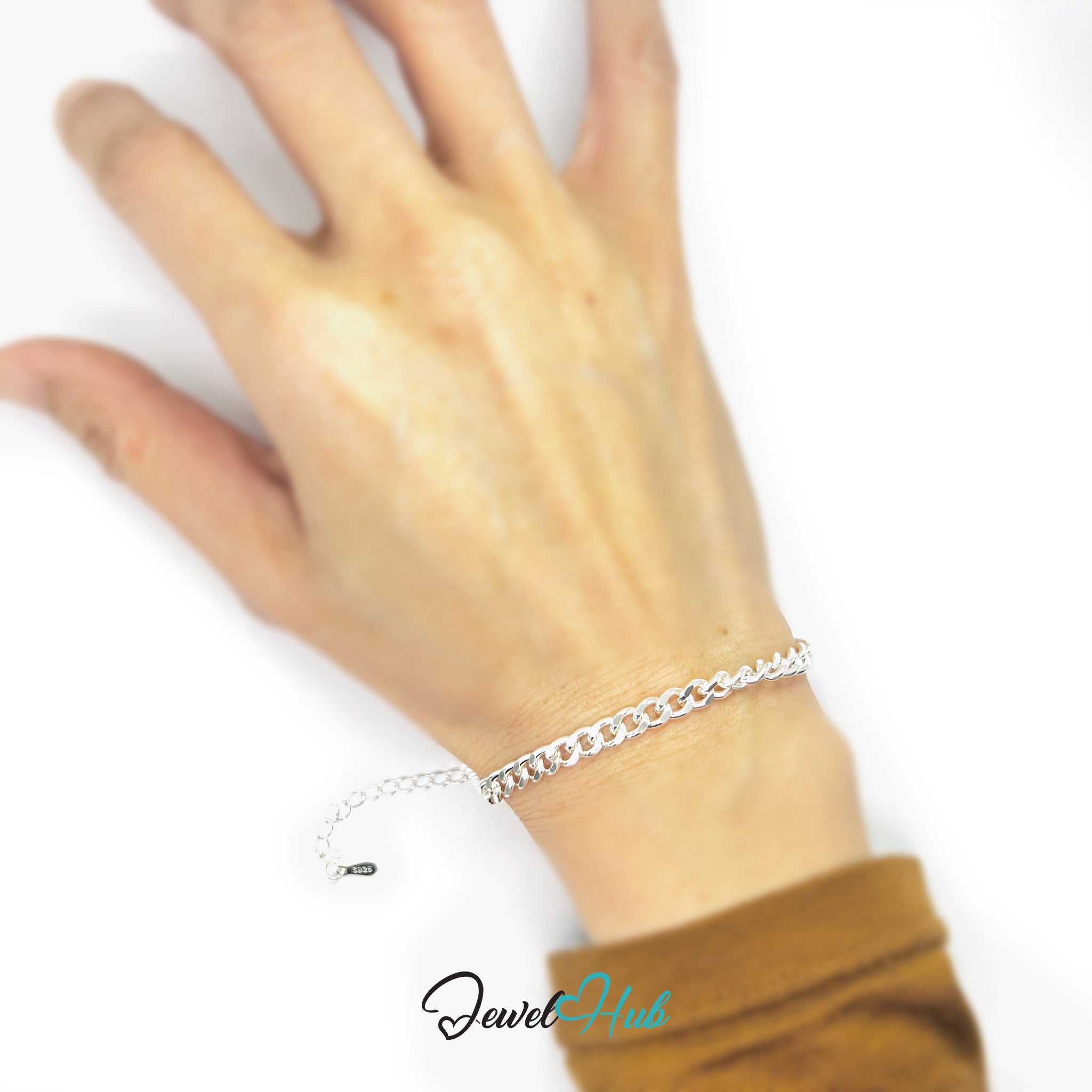 Silver bracelet on a wrist with a plain background