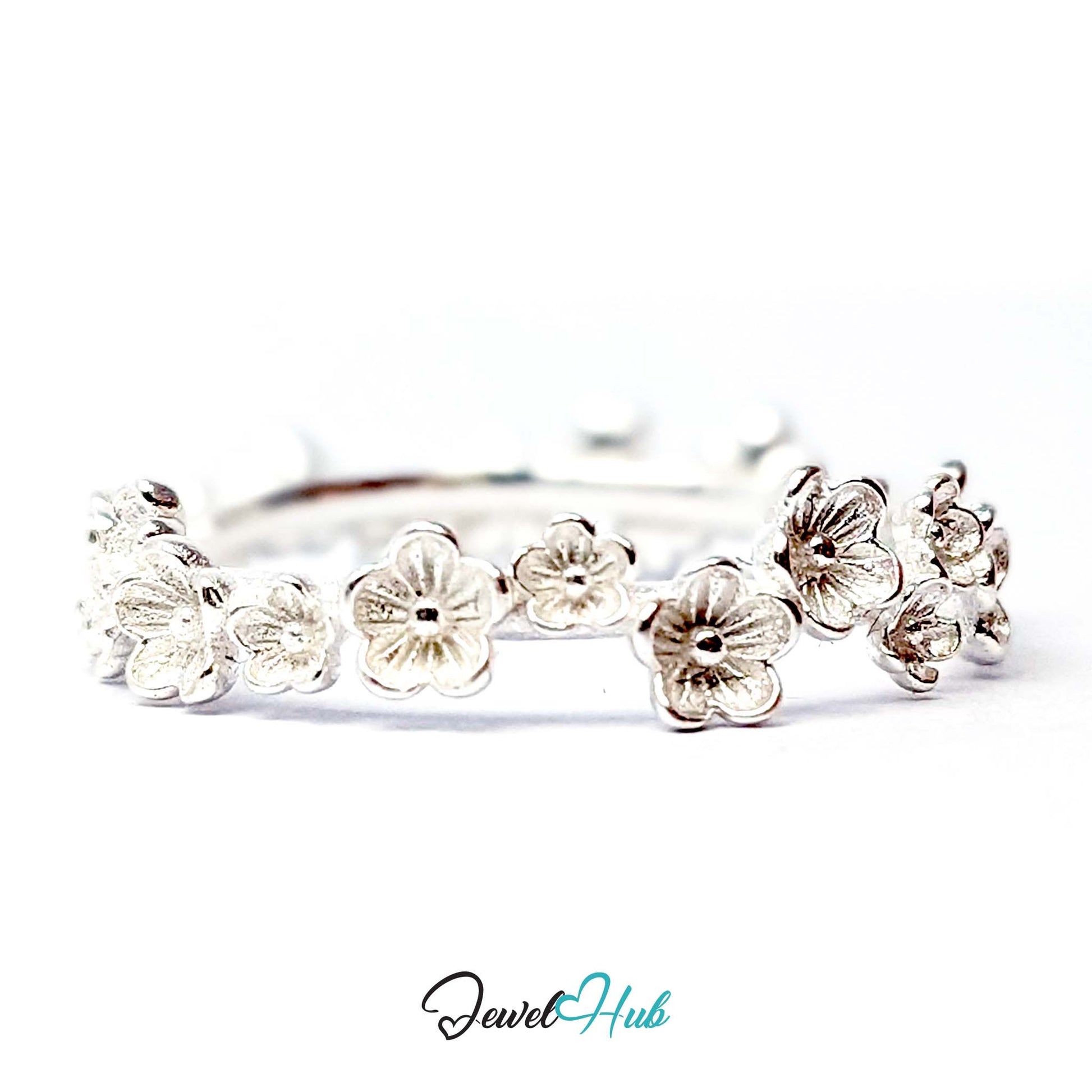 Row of five-petal blossoms across the front of the 999 fine silver band ring