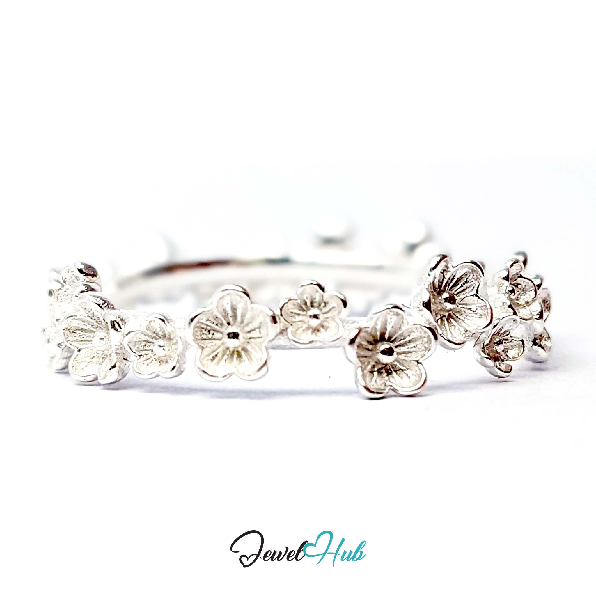 Row of five-petal blossoms across the front of the 999 fine silver band ring