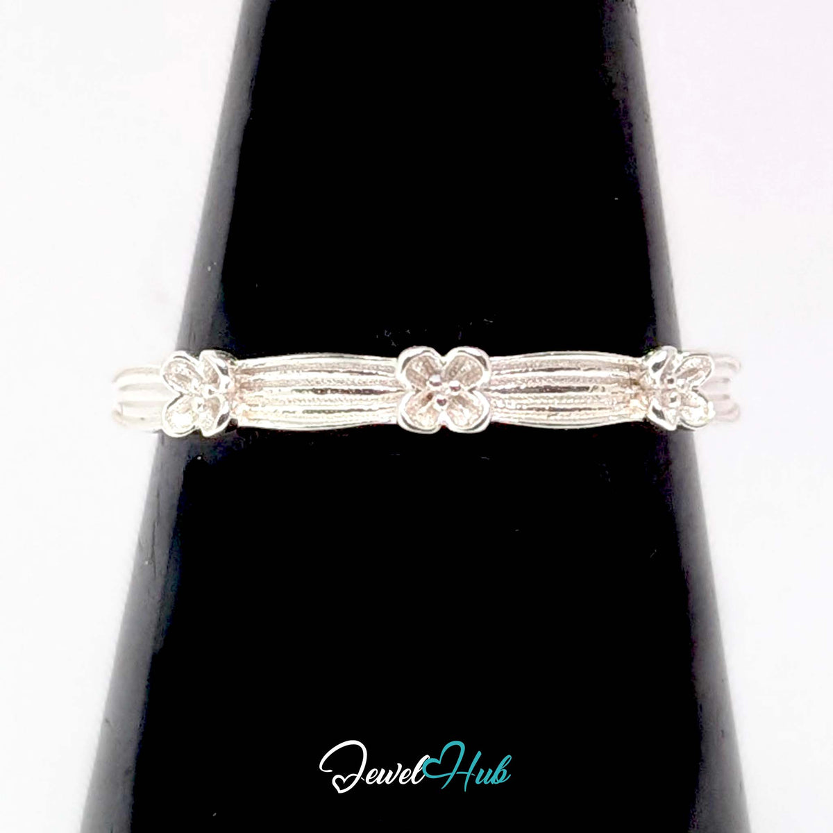 Flower Band Ring against a black cone, showing the ribbing and flower detail