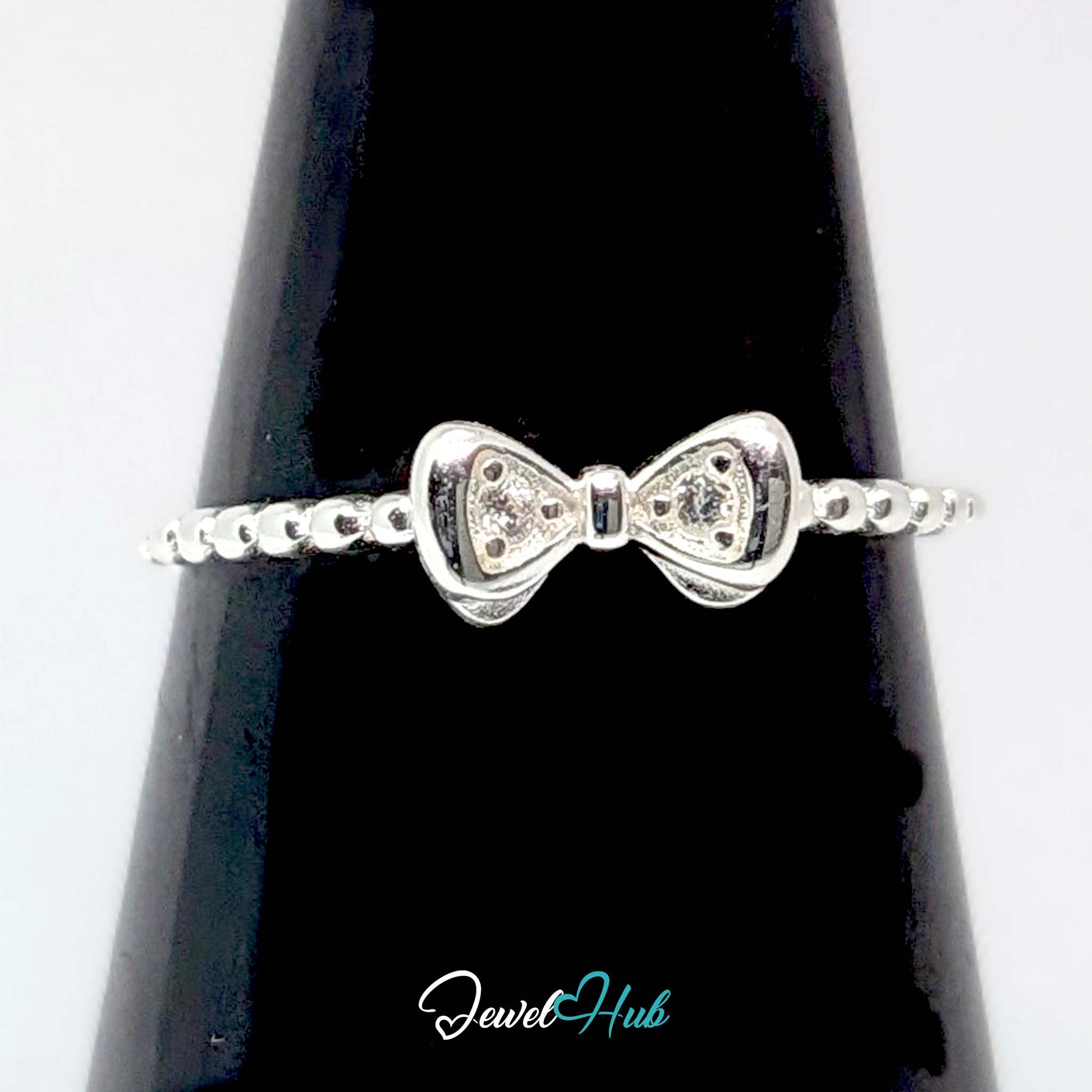Bow ring against a black cone, showing the crystal set in each loop - JewelHub