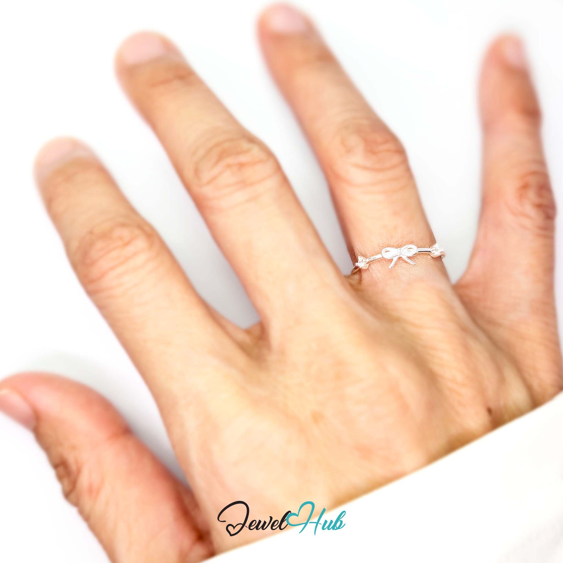 Open bow ring worn on a hand, showing the fit of the smaller J-L band - JewelHub