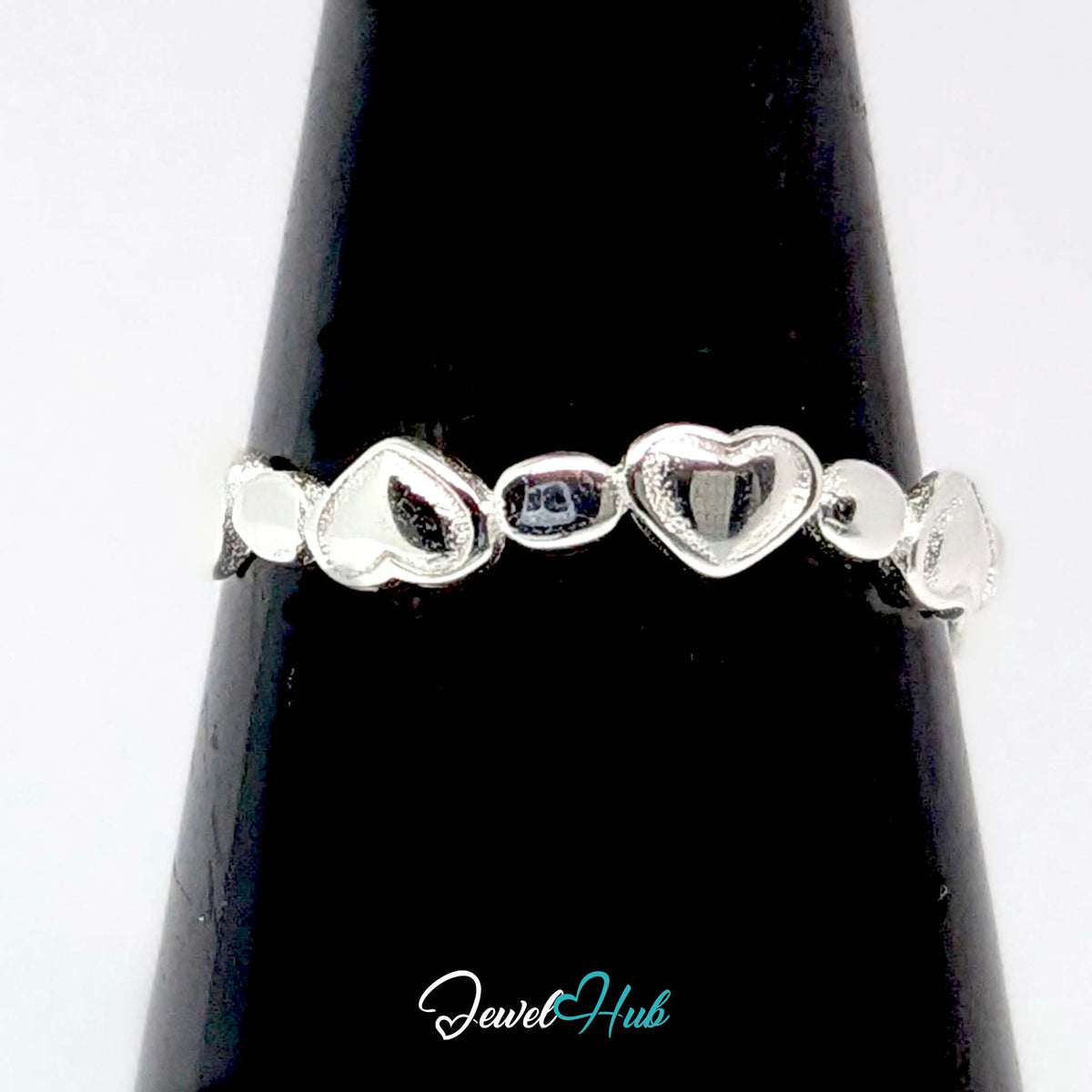 Heart band ring against a black cone, the solid hearts reading clearly - JewelHub