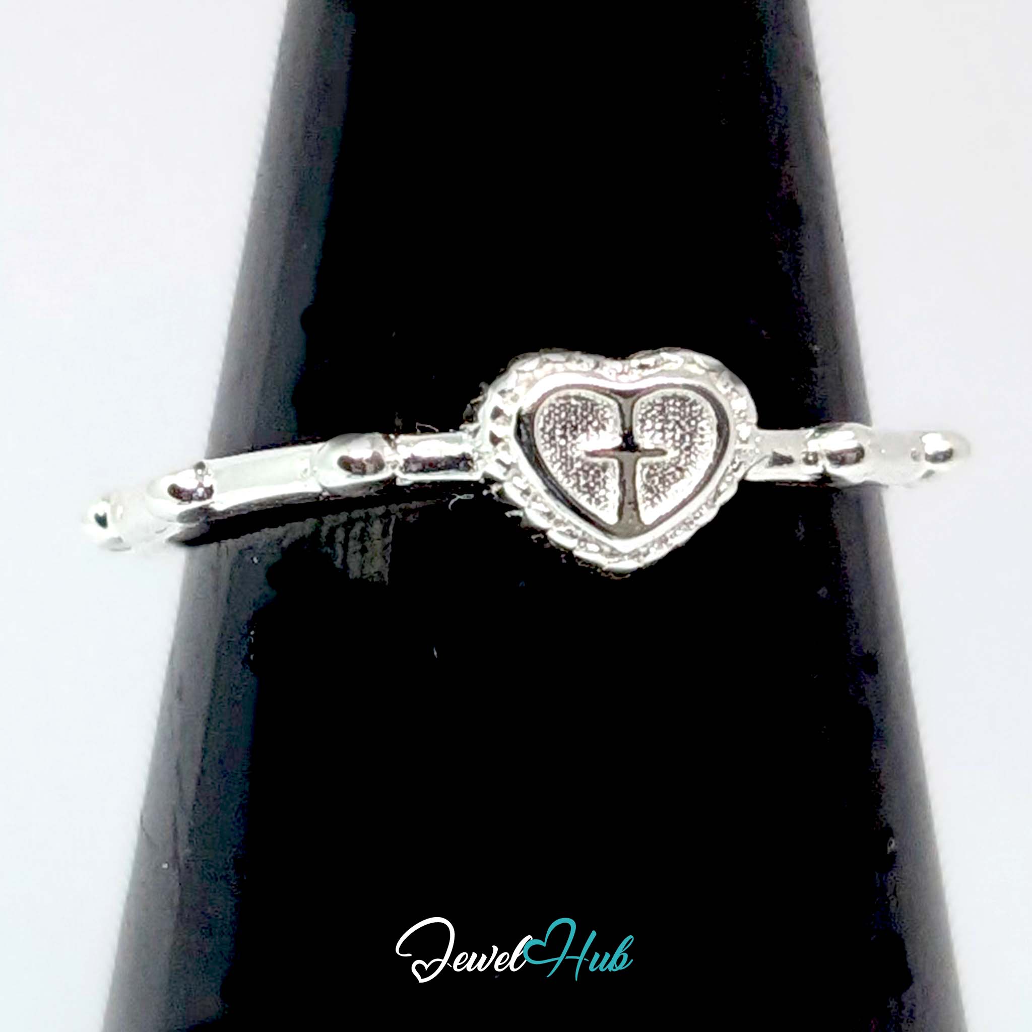 Cross heart ring against a black cone, the engraved cross clearly visible - JewelHub