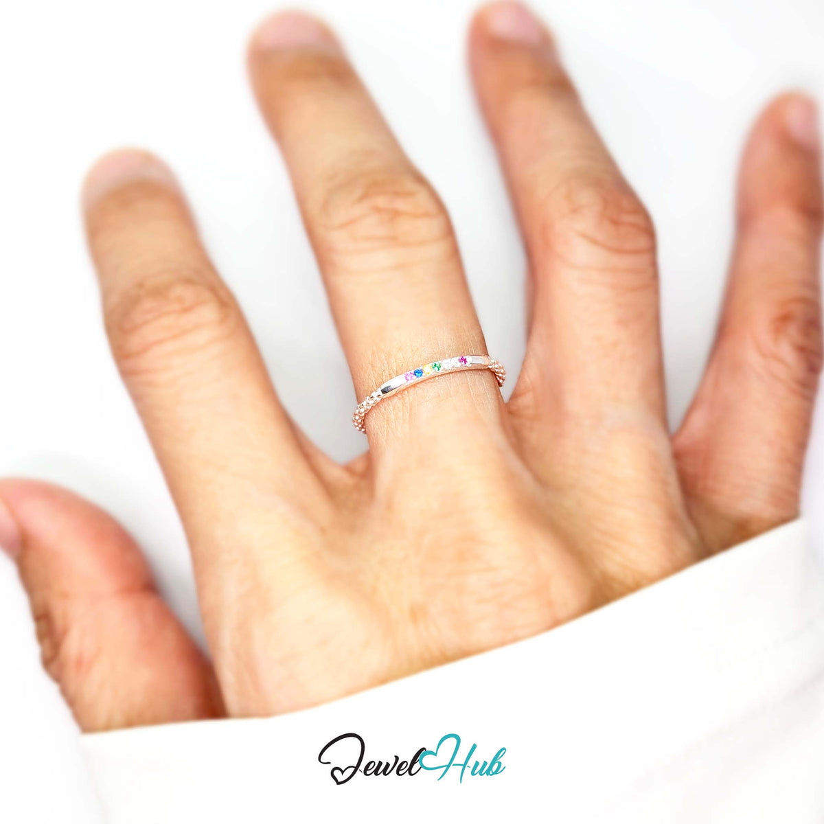 Rainbow ring worn on a hand, showing the slim beaded band - JewelHub