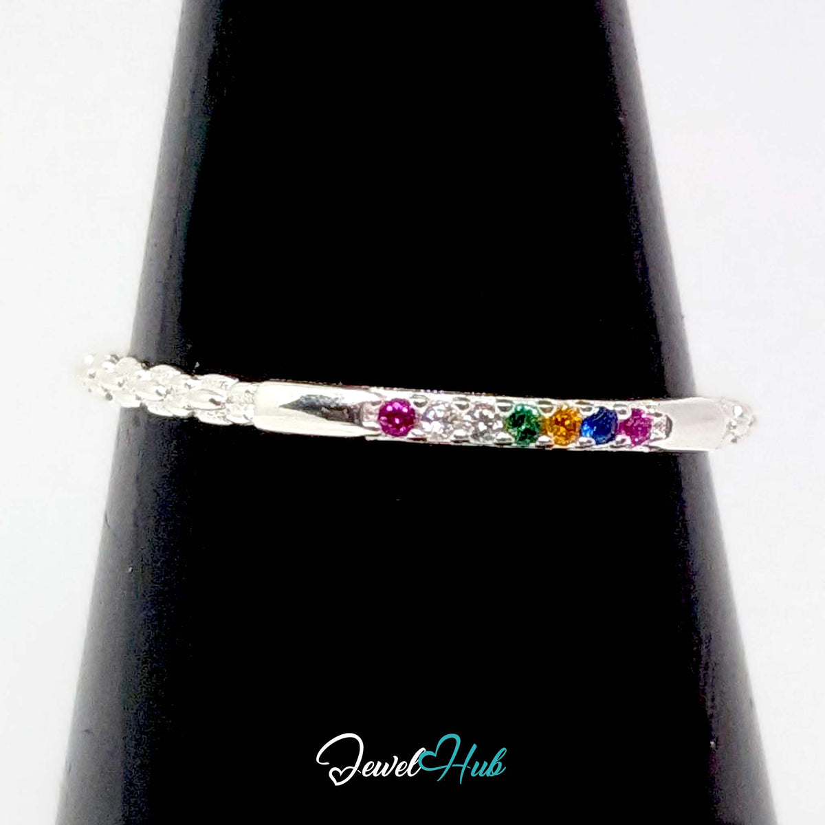 Rainbow ring on a black cone display, showing the line of six coloured stones - JewelHub