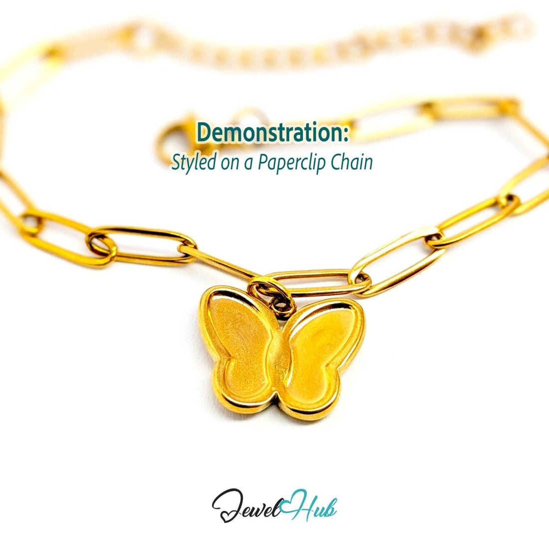 Gold butterfly charm hanging from a gold paperclip chain bracelet - JewelHub