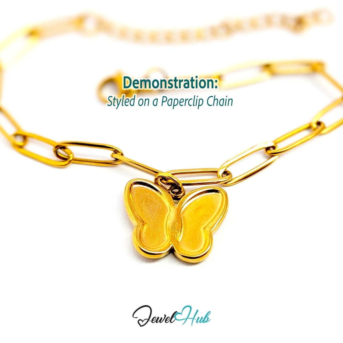 Gold butterfly charm hanging from a gold paperclip chain bracelet - JewelHub