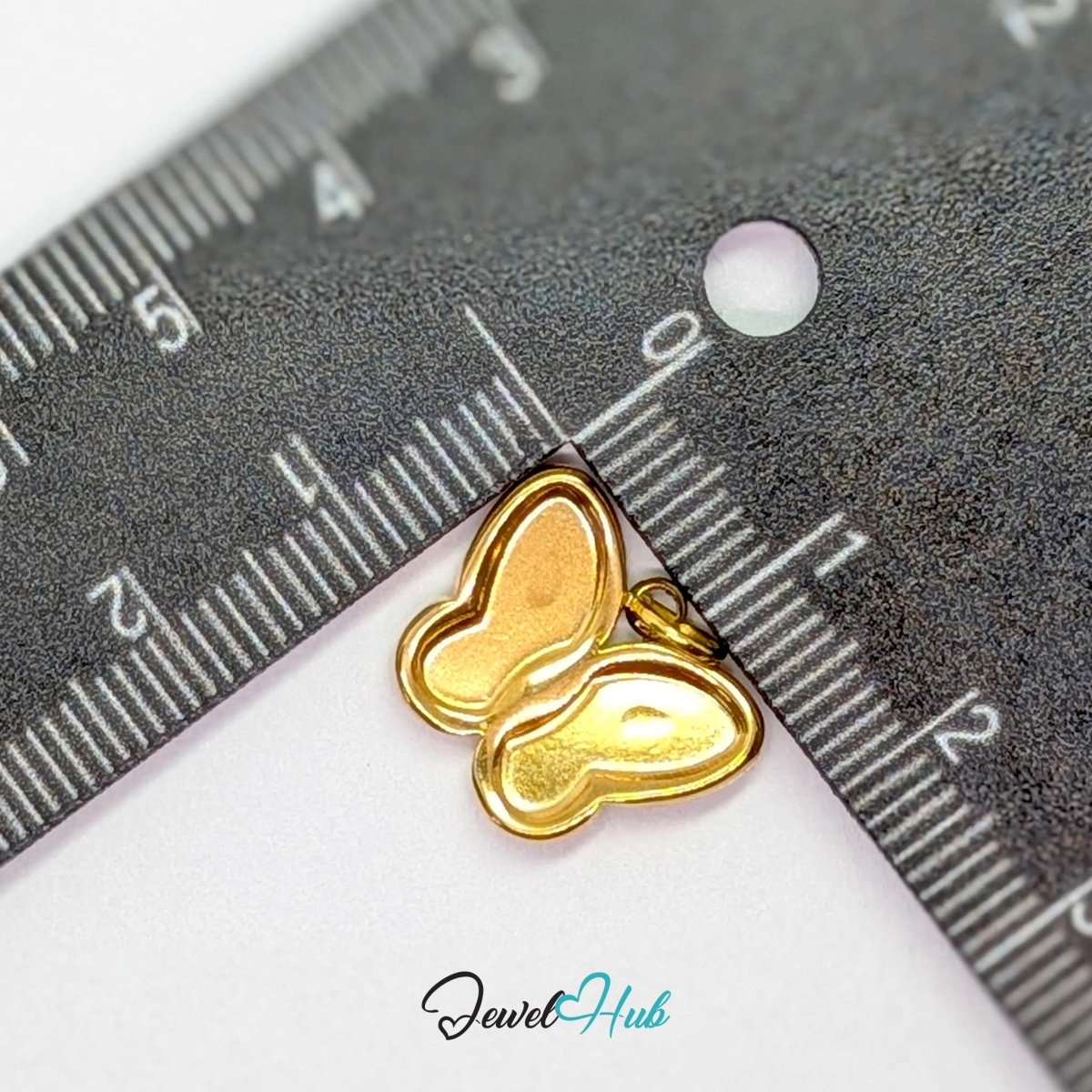 Gold butterfly charm measured against a ruler at 17mm wide by 13.5mm tall - JewelHub