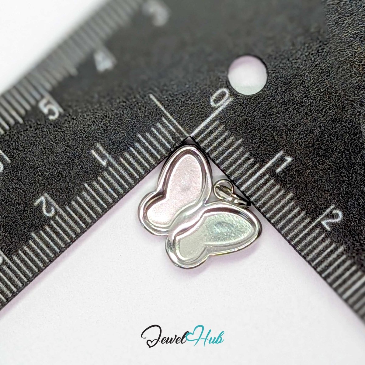 Silver butterfly charm measured against a ruler at 17mm wide by 13.5mm tall - JewelHub