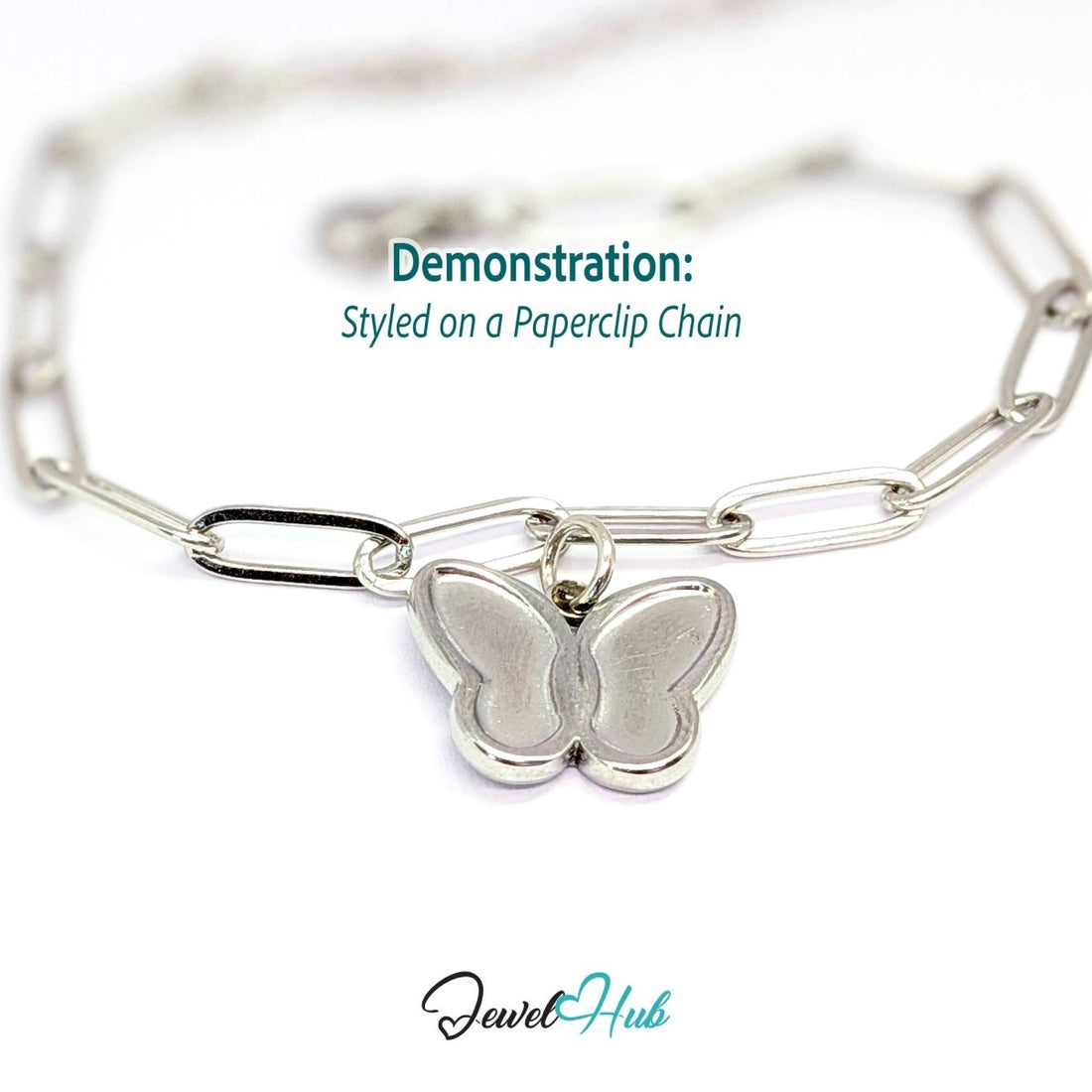 Silver butterfly charm hanging from a silver paperclip chain bracelet - JewelHub