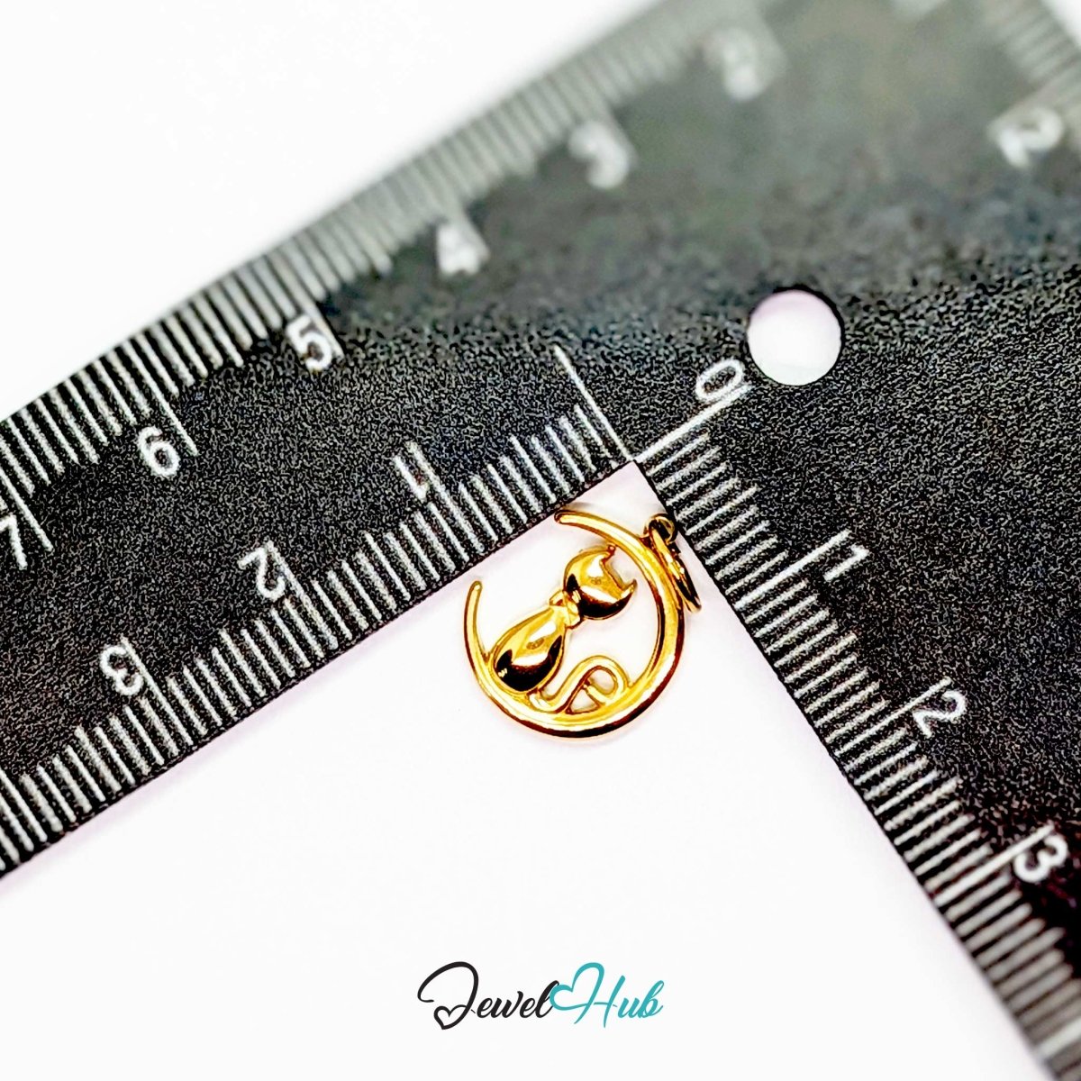 Gold cat and moon charm measured against a ruler at 12.5mm wide by 15mm tall - JewelHub
