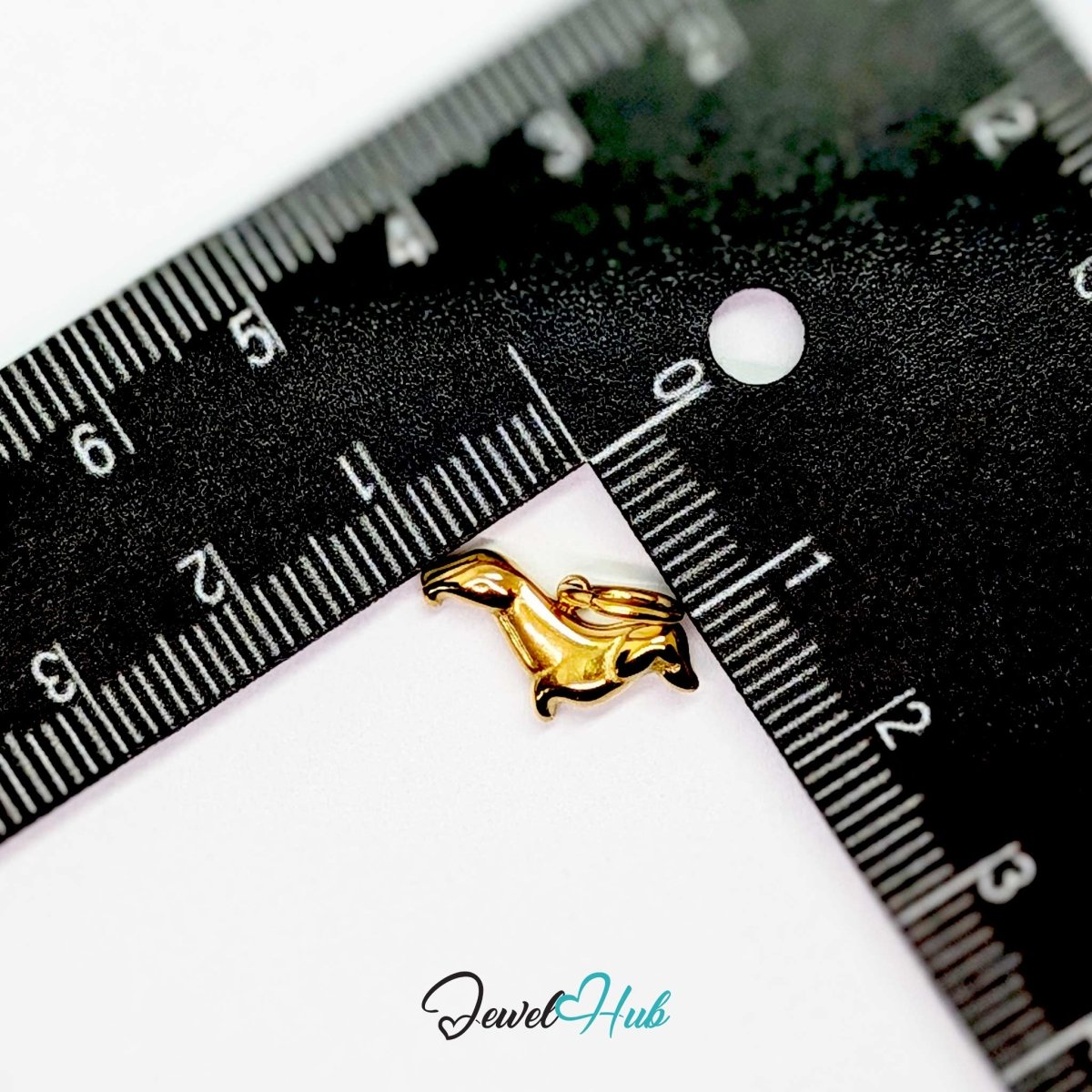 Gold dachshund charm measured against a ruler at 16mm long by 9.8mm tall - JewelHub