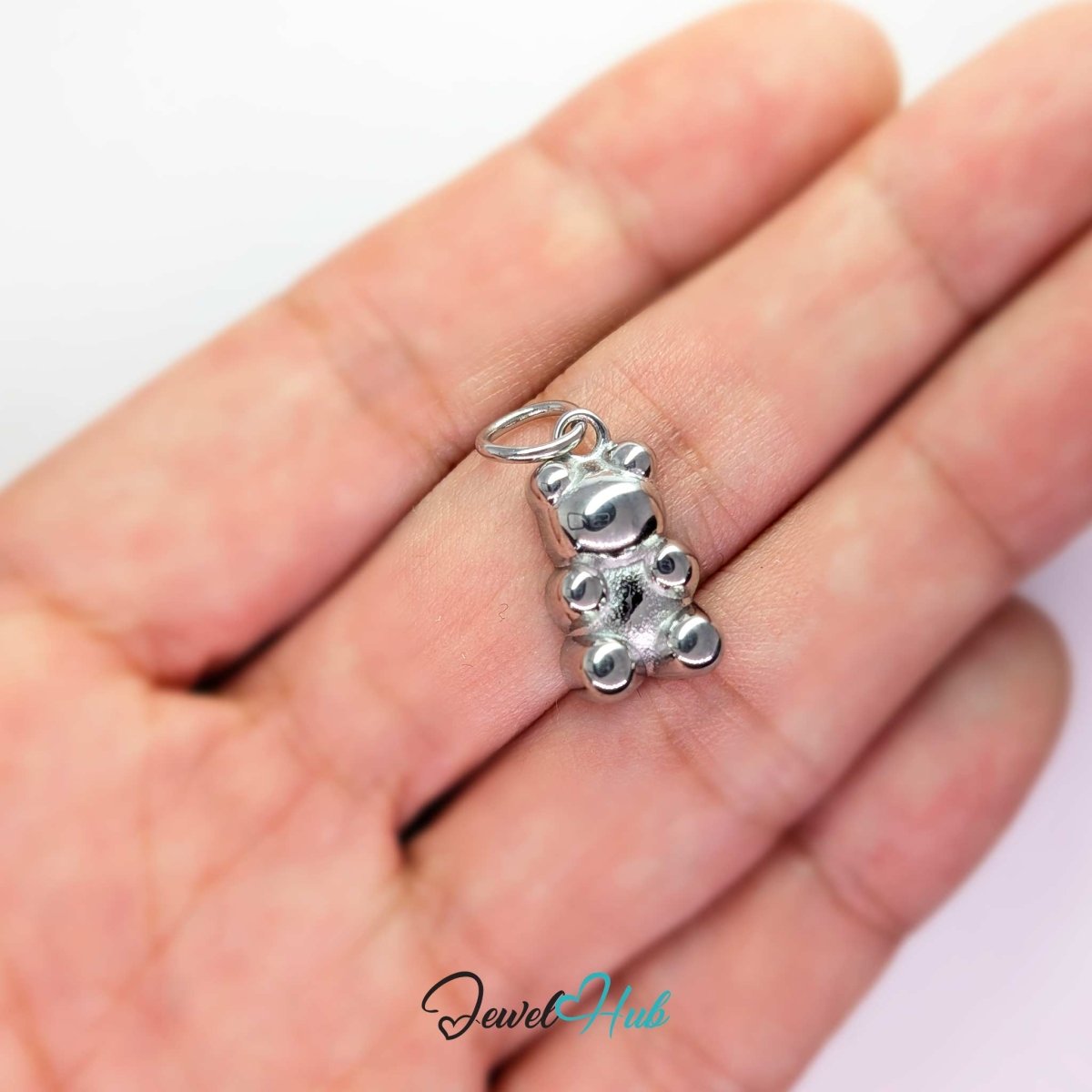 Silver Classic Gummy Bear charm held in the hand to show its size against a fingertip - JewelHub