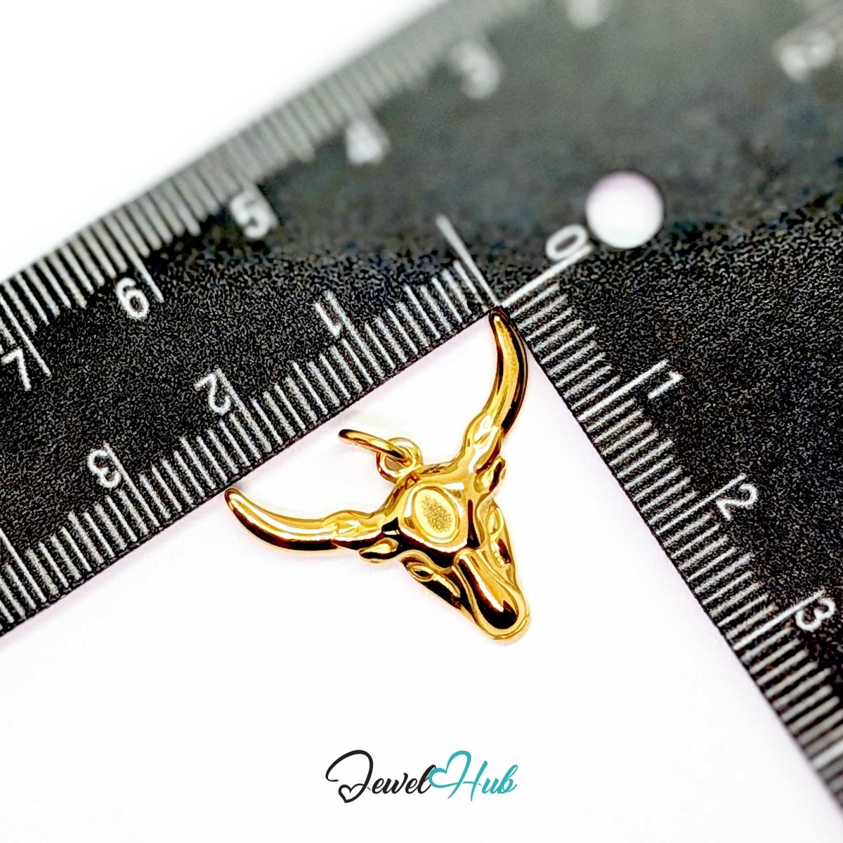 Gold longhorn bull charm measured against a ruler at 25mm wide by 20.5mm tall - JewelHub