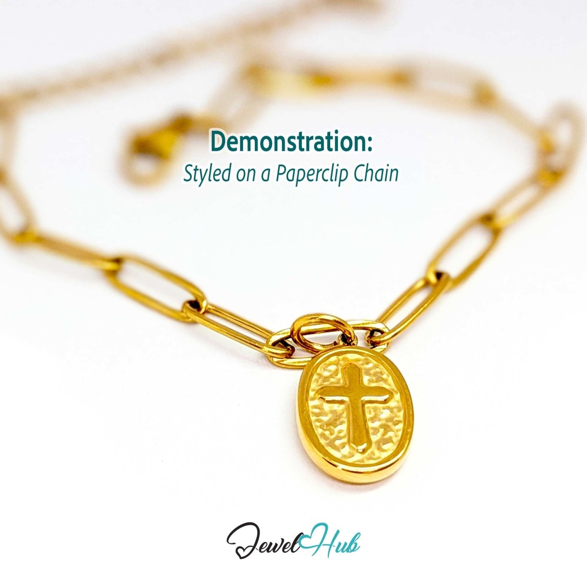 Oval cross medallion charm in gold stainless steel - styled on a gold paperclip chain bracelet - JewelHub