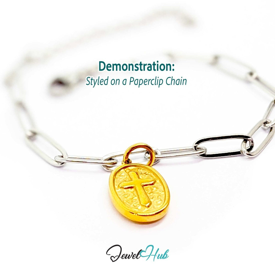 Oval cross medallion charm in gold stainless steel - styled on a silver paperclip chain bracelet - JewelHub
