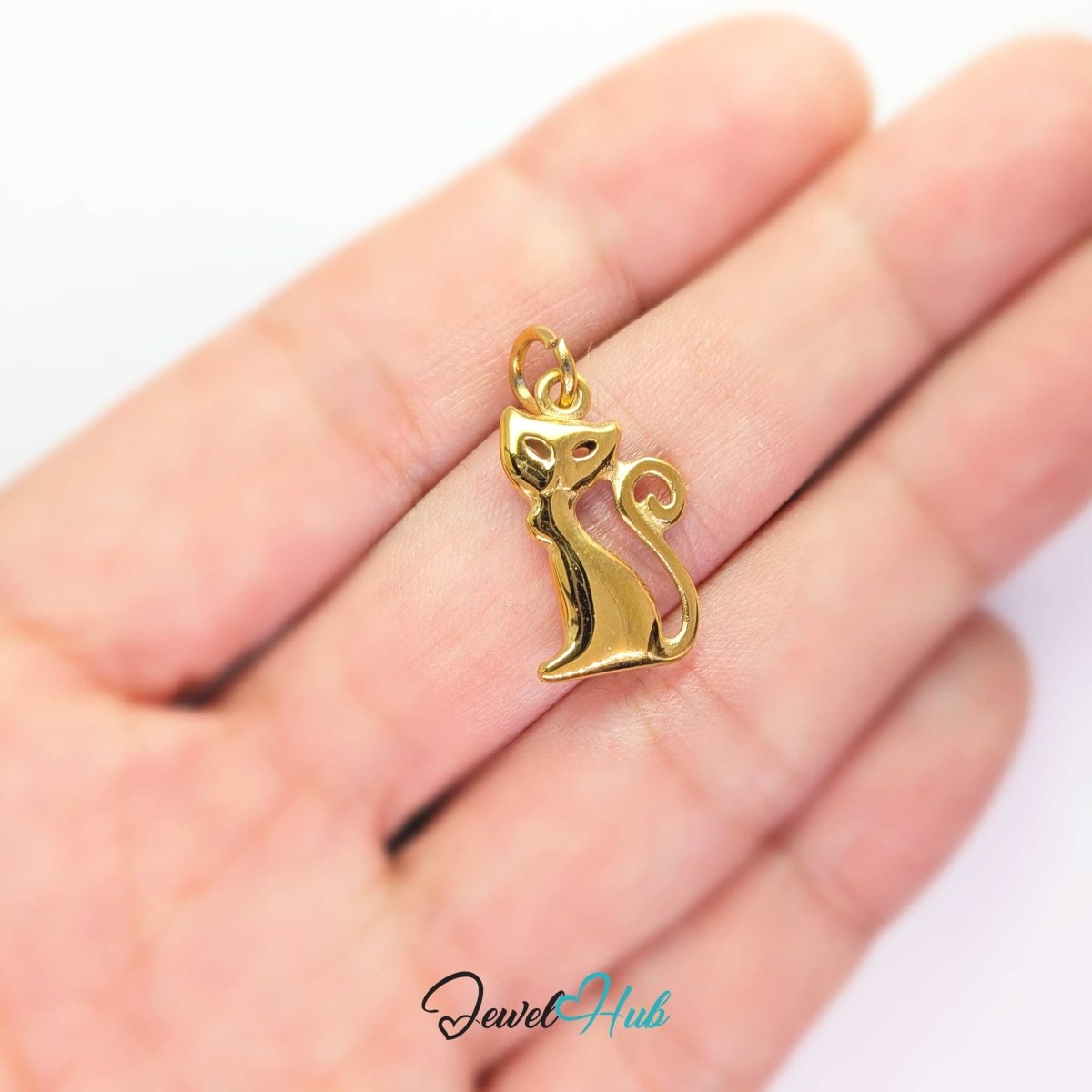 Gold standing cat charm held in the hand to show its size against a fingertip - JewelHub