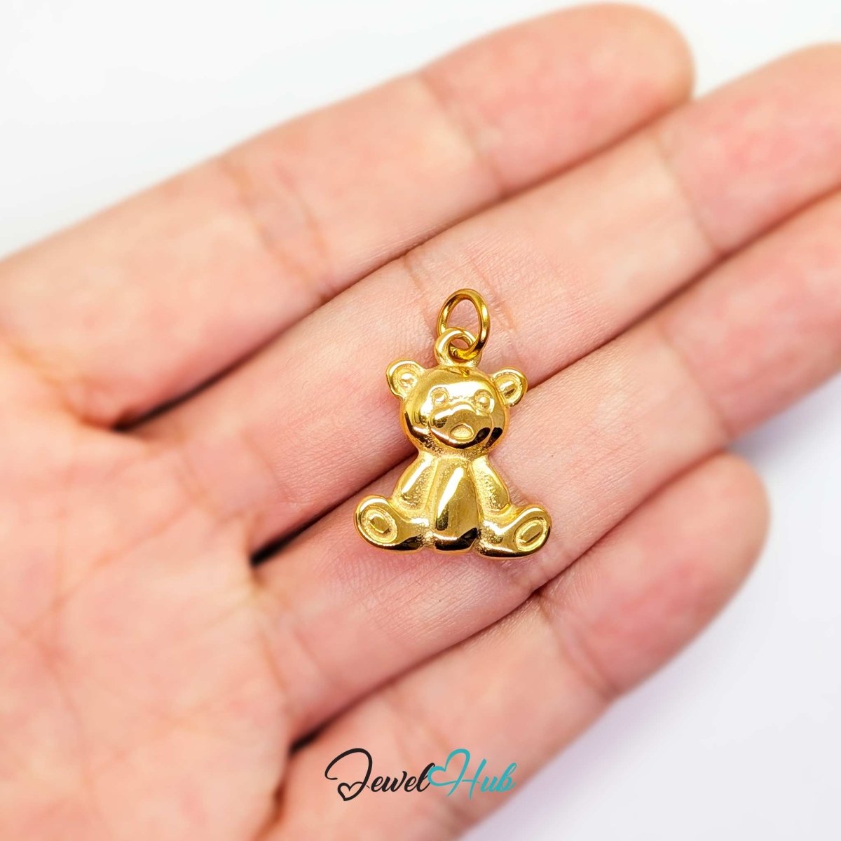 Gold Classic Teddy Bear charm held in the hand to show its size against a fingertip - JewelHub