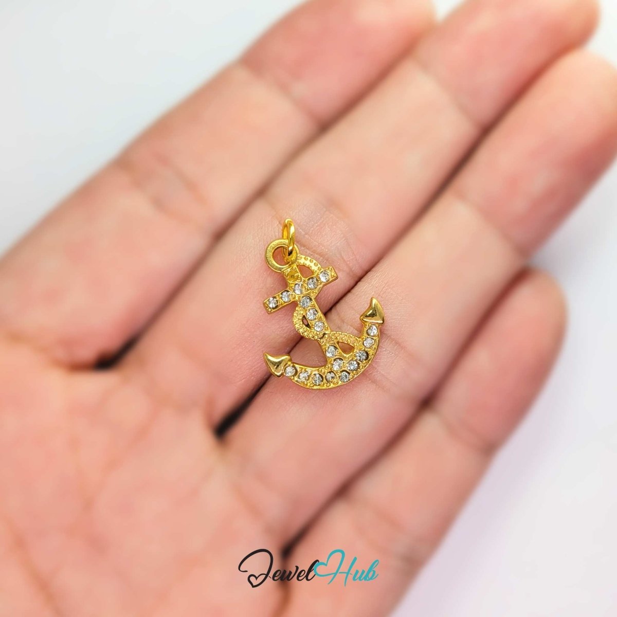 Anchor charm in gold stainless steel with a coiled rope and pave crystals - held in the hand for scale - JewelHub