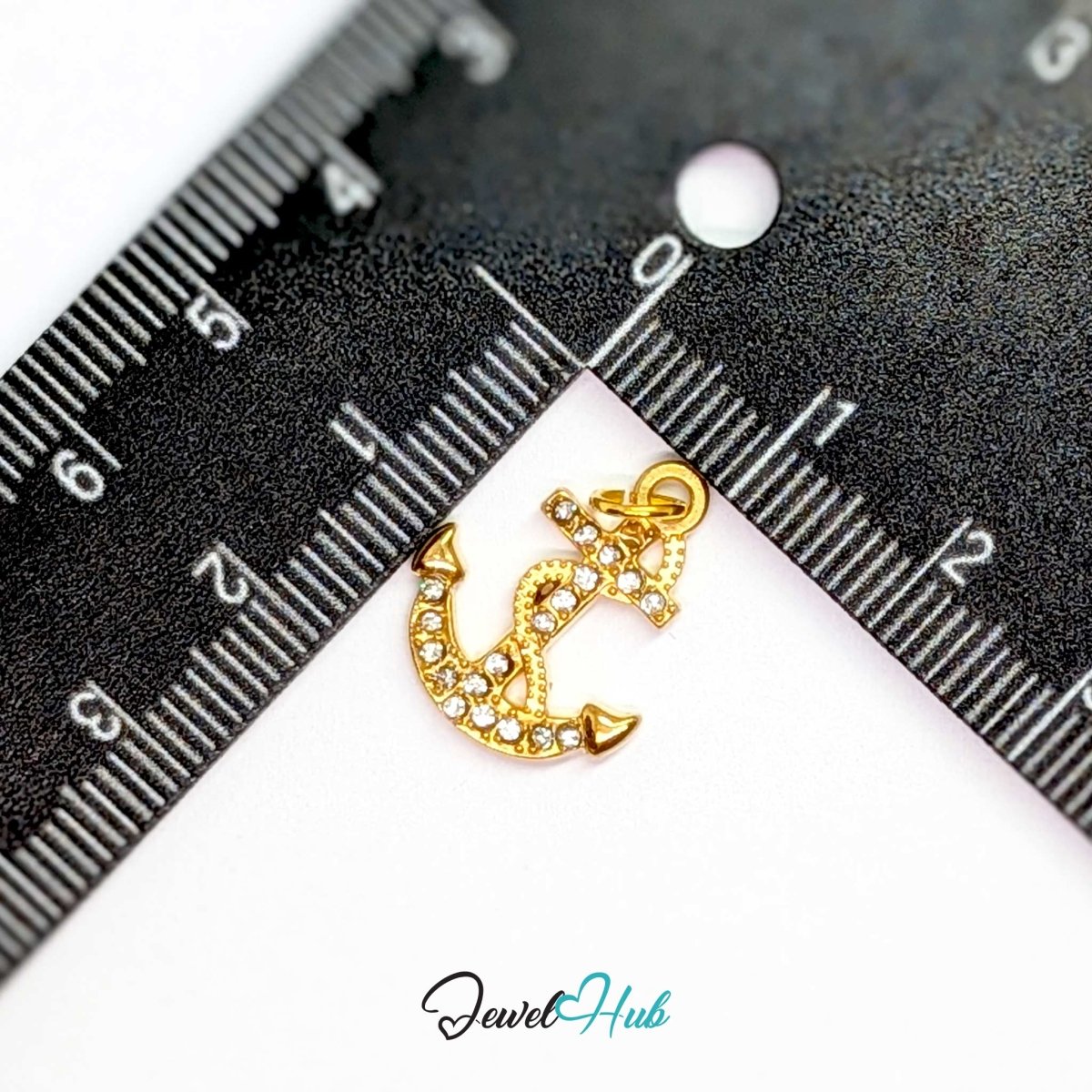 Anchor charm in gold stainless steel with a coiled rope and pave crystals - beside a ruler for scale - JewelHub