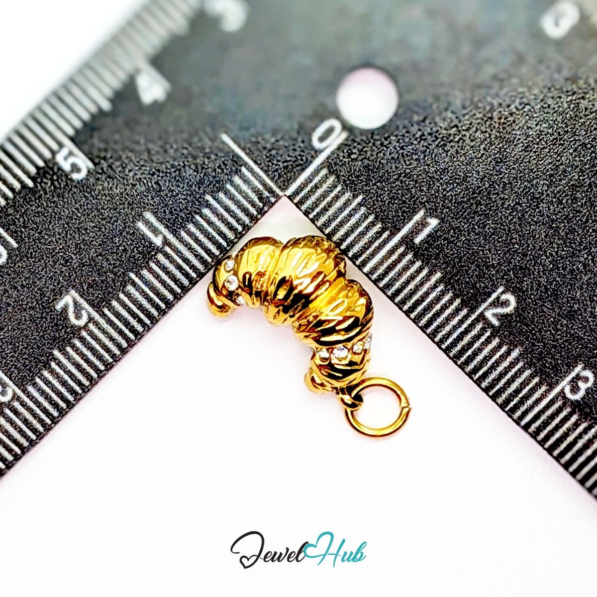 Croissant charm in gold stainless steel with clear crystals - beside a ruler for scale - JewelHub
