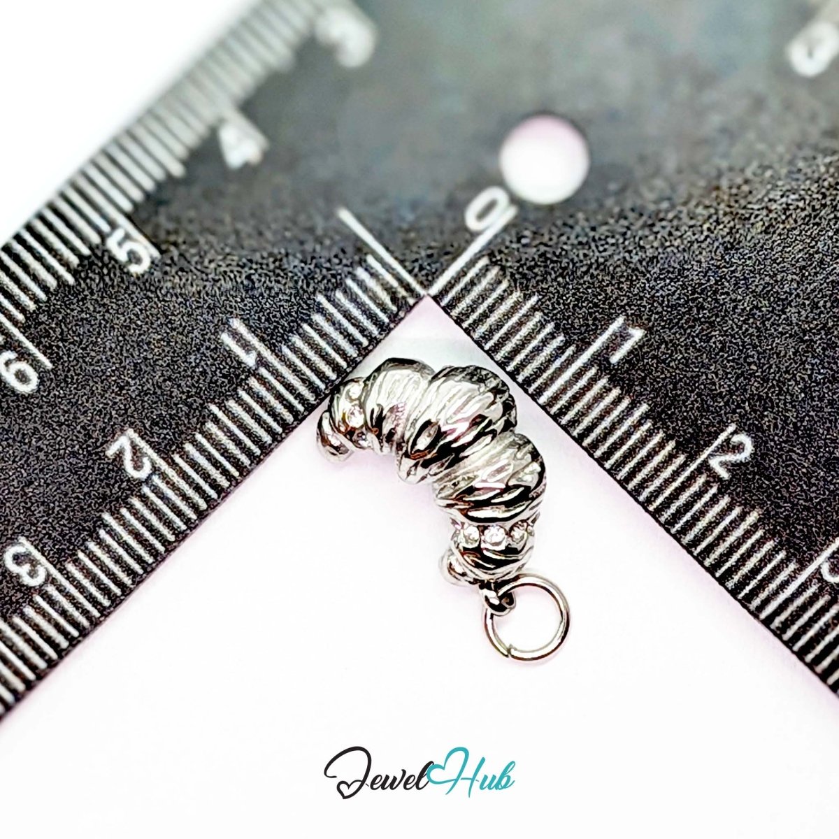 Croissant charm in silver stainless steel with clear crystals - beside a ruler for scale - JewelHub