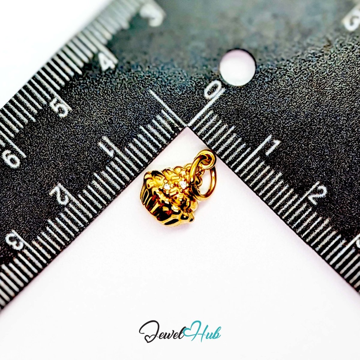 Cupcake charm in gold stainless steel with clear crystals - beside a ruler for scale - JewelHub