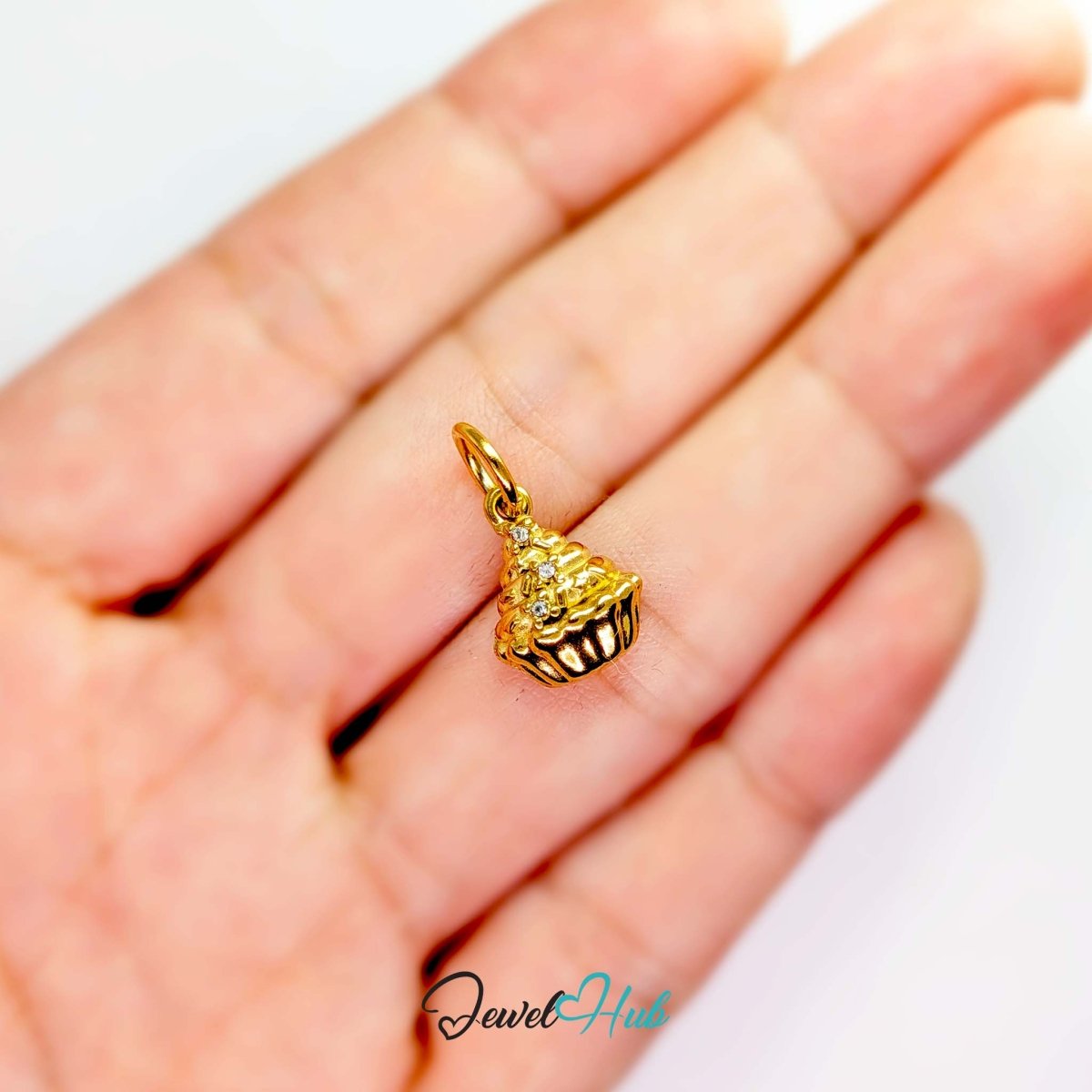 Cupcake charm in gold stainless steel with clear crystals - held in the hand for scale - JewelHub
