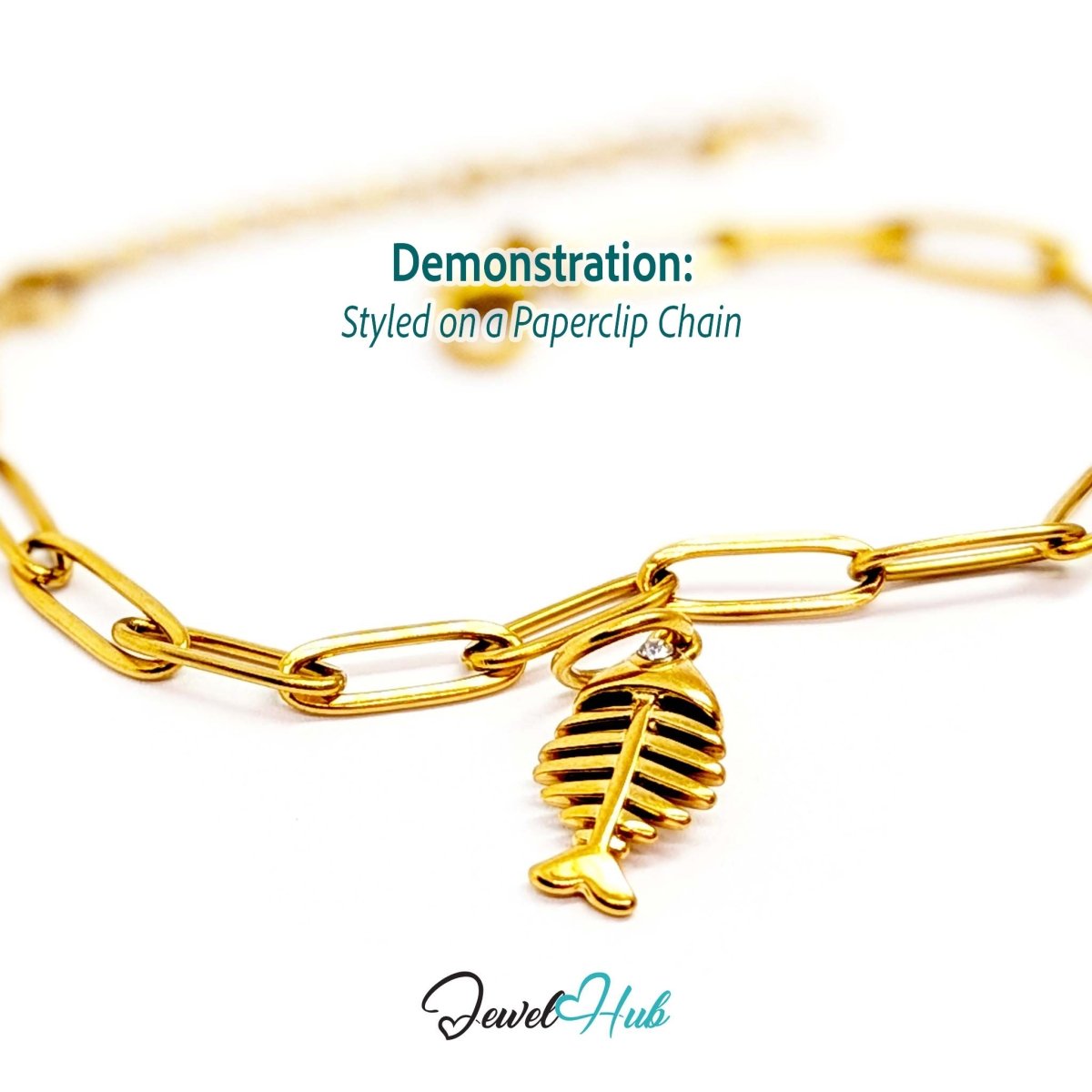 Fish bone charm in gold stainless steel with a crystal eye - styled on a gold paperclip chain bracelet - JewelHub