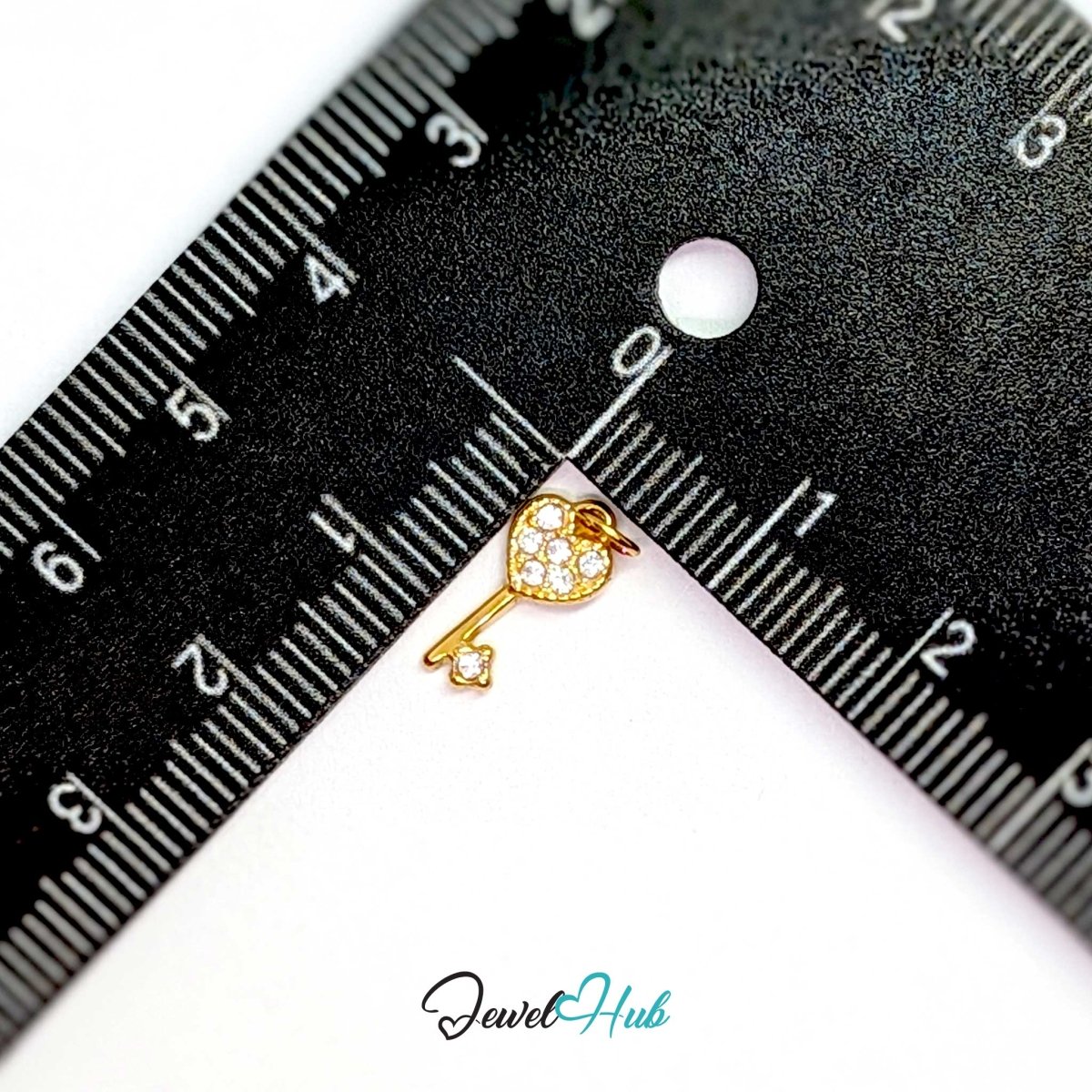 Mini heart key charm in gold stainless steel set with crystals - beside a ruler for scale - JewelHub