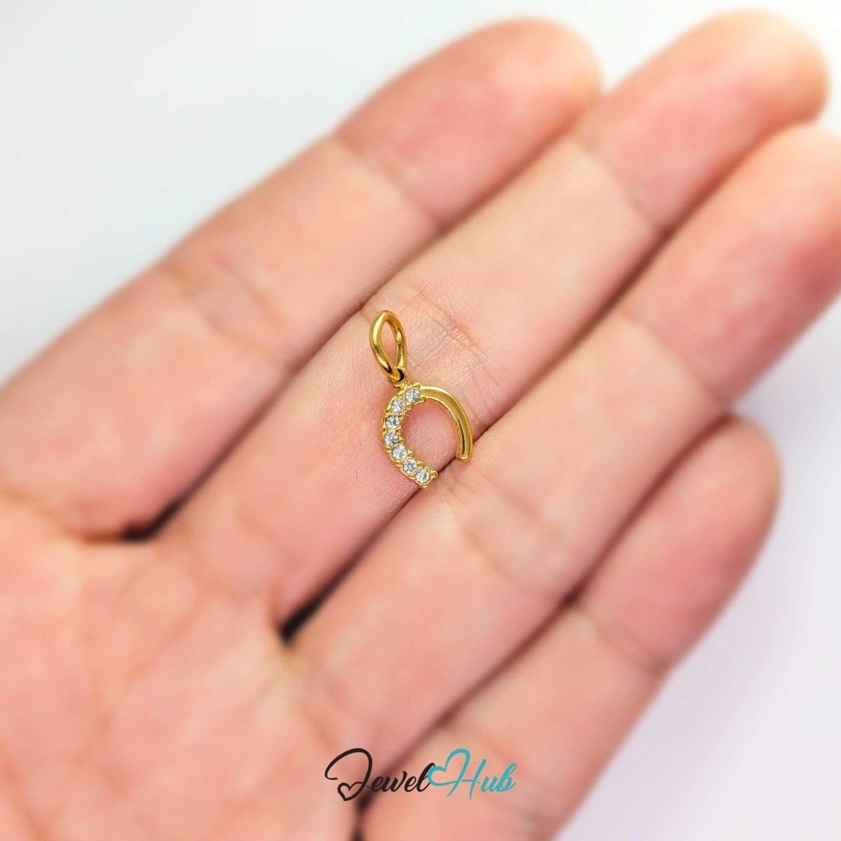 Mini horseshoe charm in gold stainless steel with seven crystals - held in the hand for scale - JewelHub