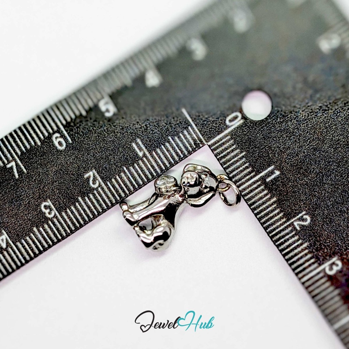 Silver sitting puppy charm measured against a ruler at 10.7mm wide by 19.6mm tall - JewelHub