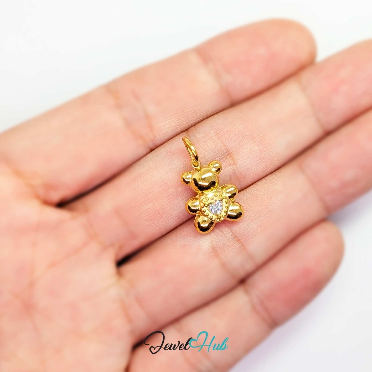 Small gold Crystal Solitaire Heart Bear charm held in the hand to show its size against a fingertip - JewelHub