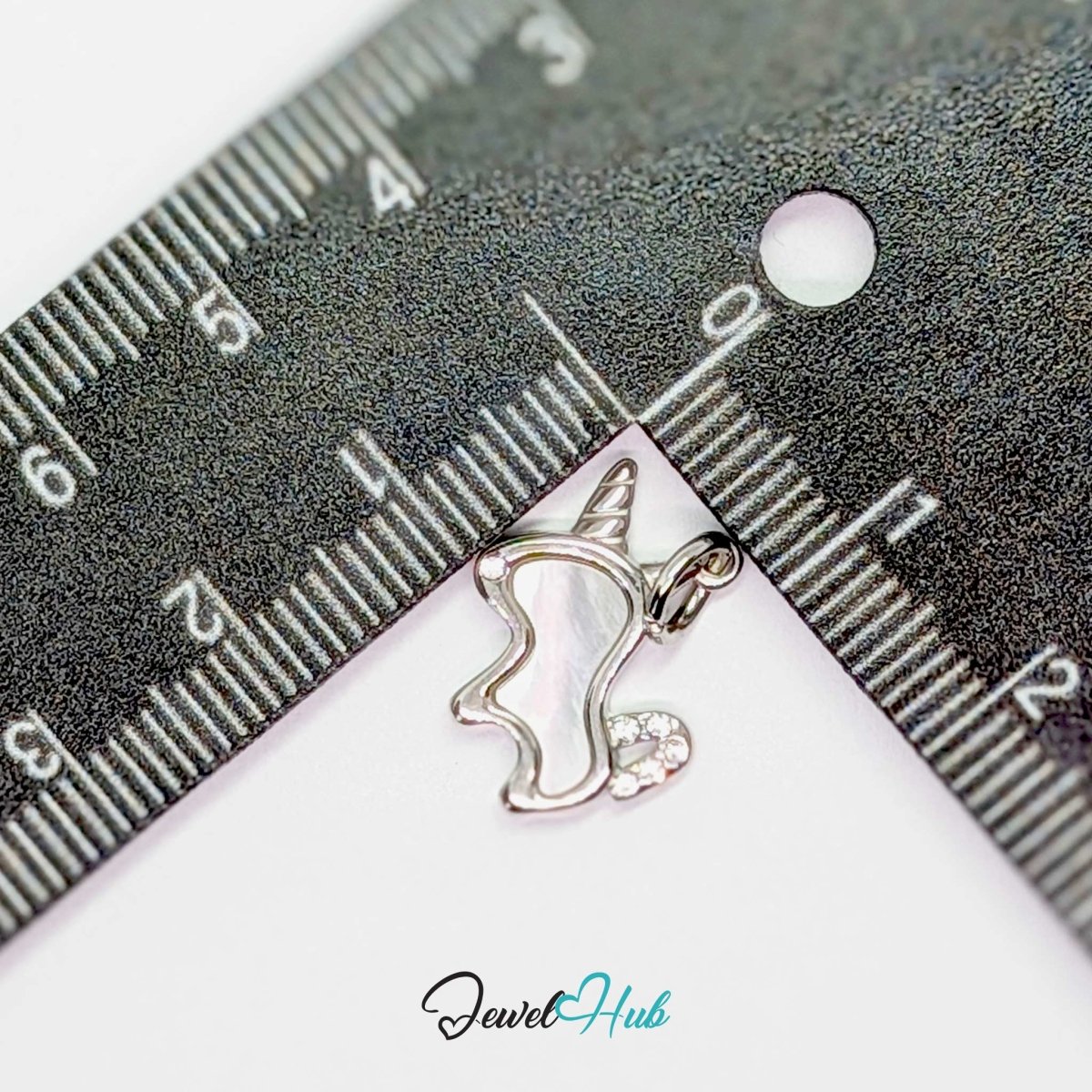 Silver unicorn charm measured against a ruler at 17mm wide by 12mm tall - JewelHub