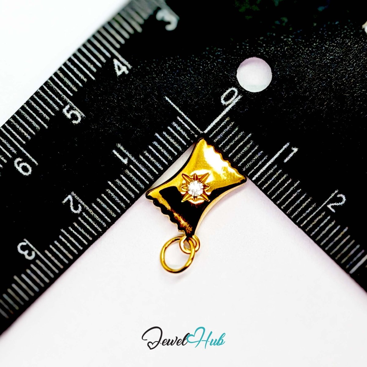 Wrapped sweet charm in gold stainless steel with a clear crystal - beside a ruler for scale - JewelHub